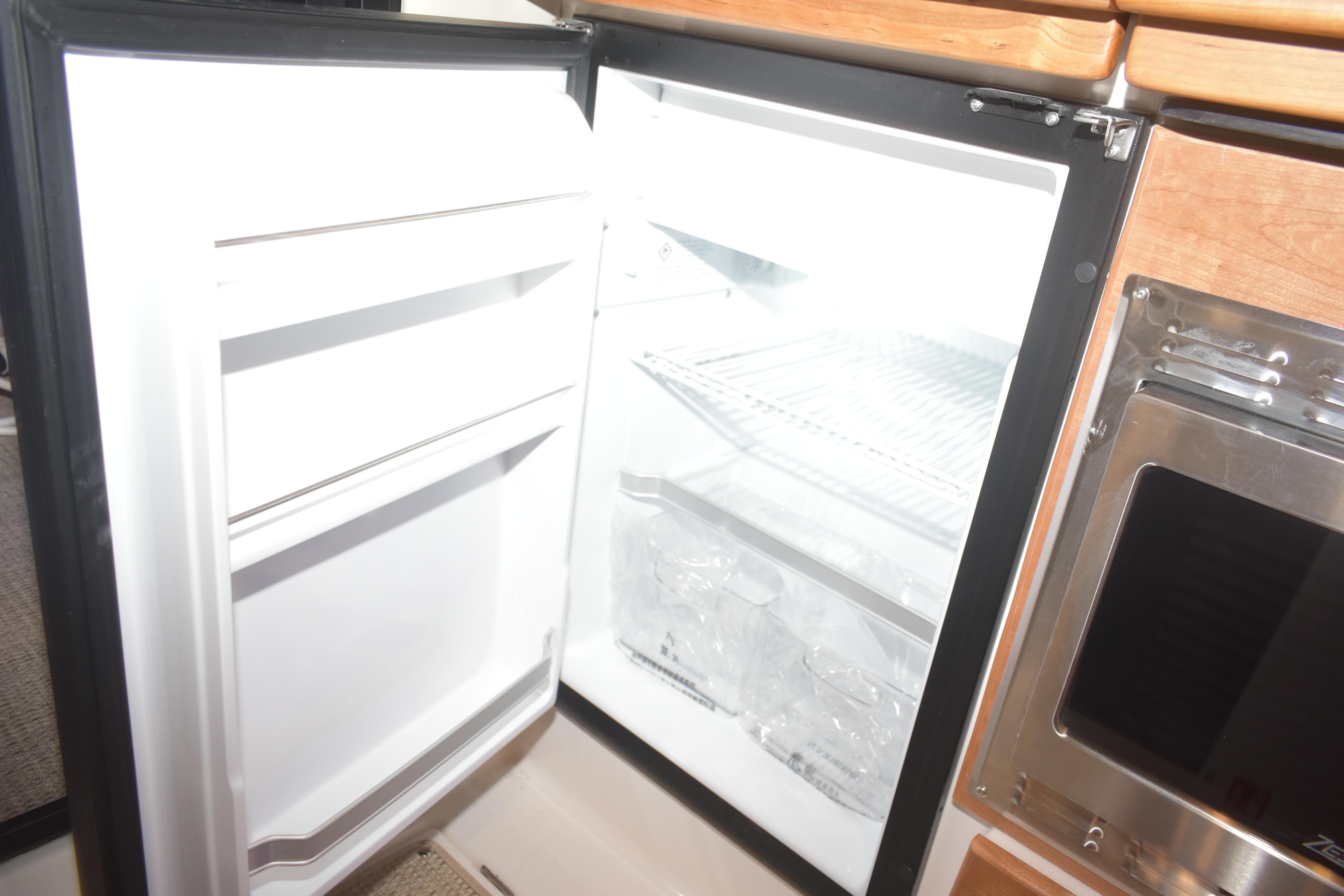 Open refrigerator inside 2026 Cutwater C-32 CB boat, showcasing interior shelves and storage.