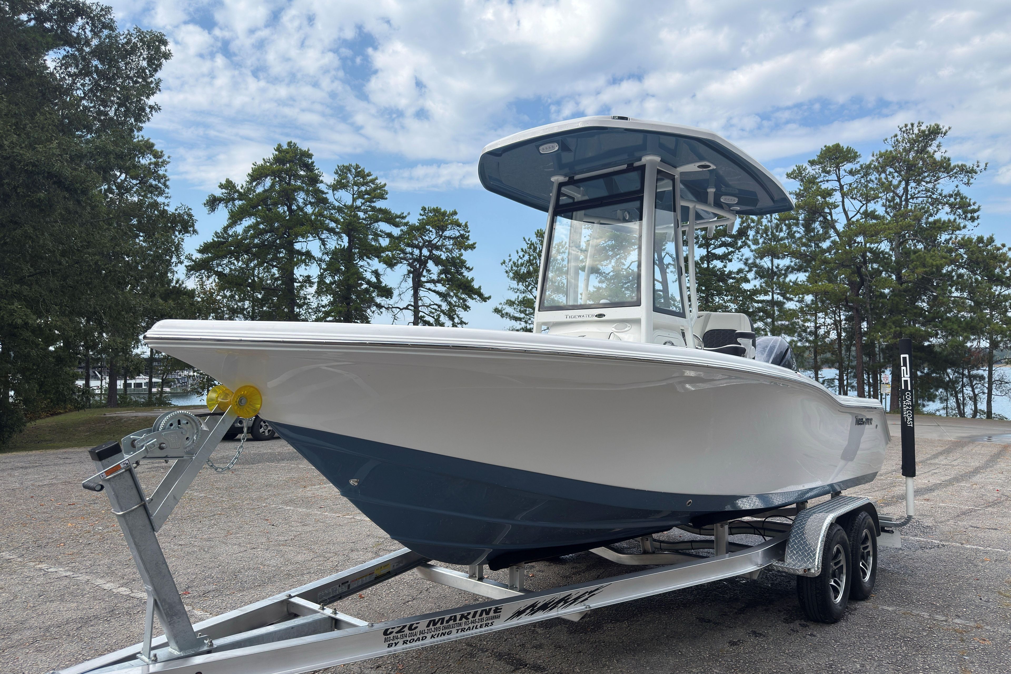 2026 Tidewater 210 CC Adventure boat on trailer, parked near trees under a cloudy sky.