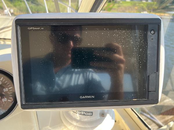 A Garmin GPS device on a boat, with a man reflected in the screen.