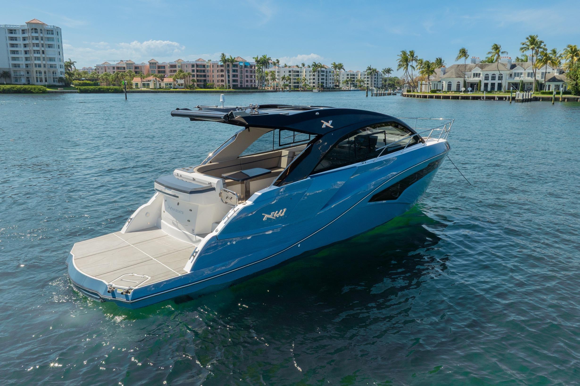 2025 NX Boats NX41 HORIZON yacht on serene water with luxury waterfront backdrop.