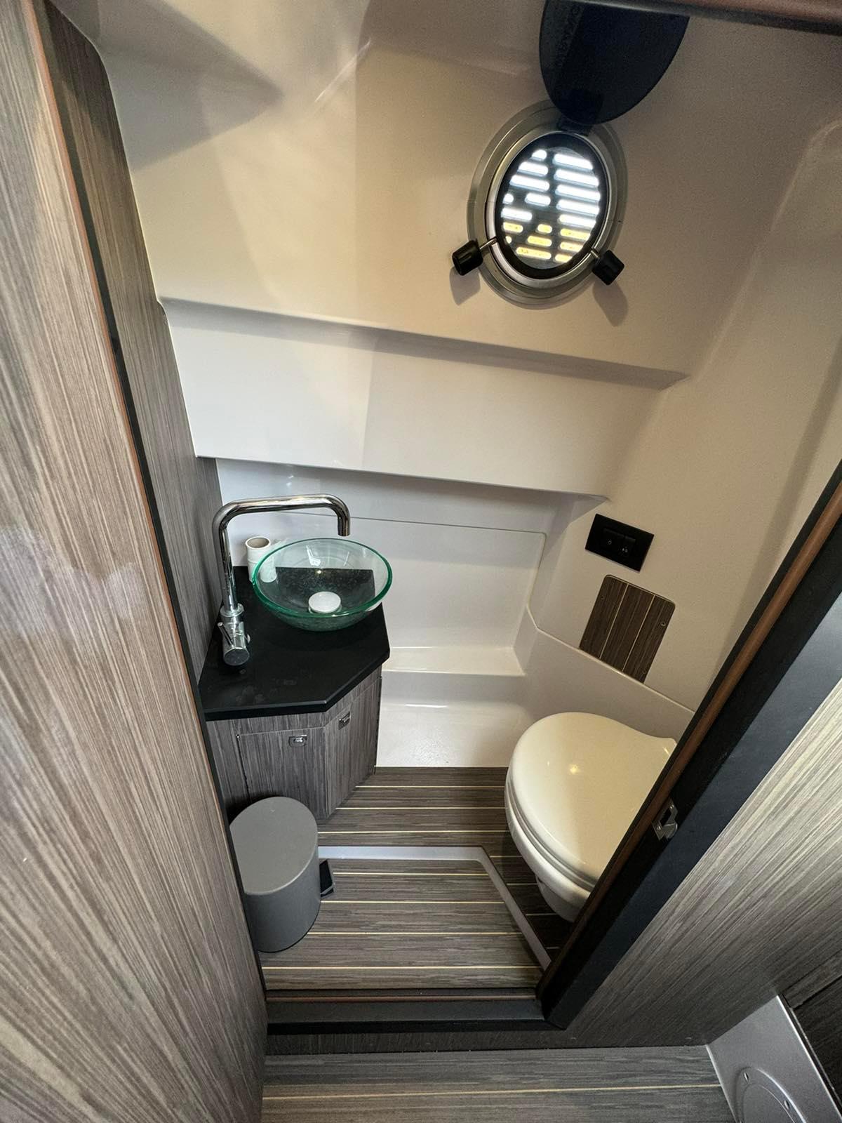 2022 Ranieri Cayman 28 Executive Trofeo bathroom with modern fixtures and porthole window.