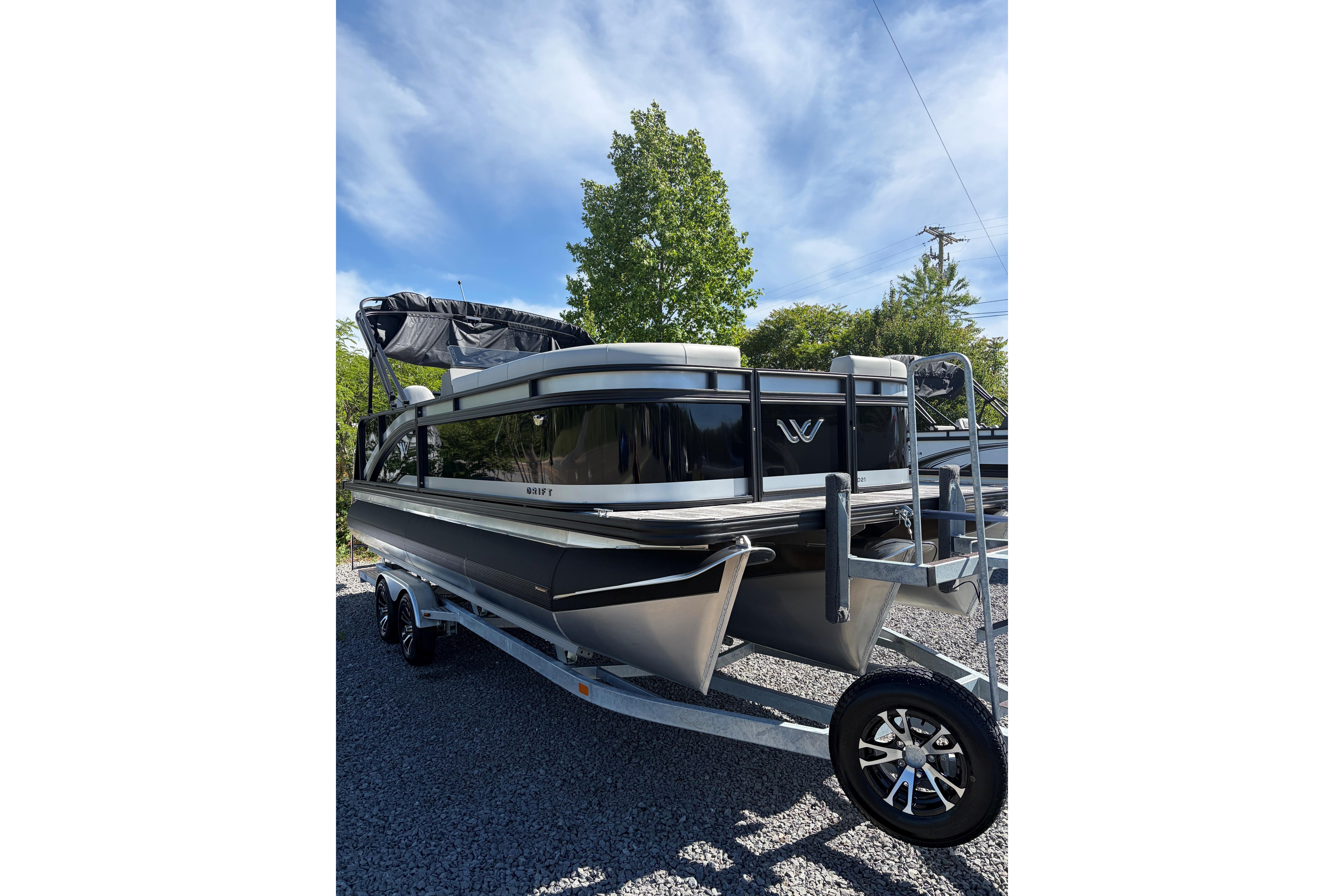 2026 Whisper D21 XRE CRUISE pontoon boat on trailer, parked outdoors.