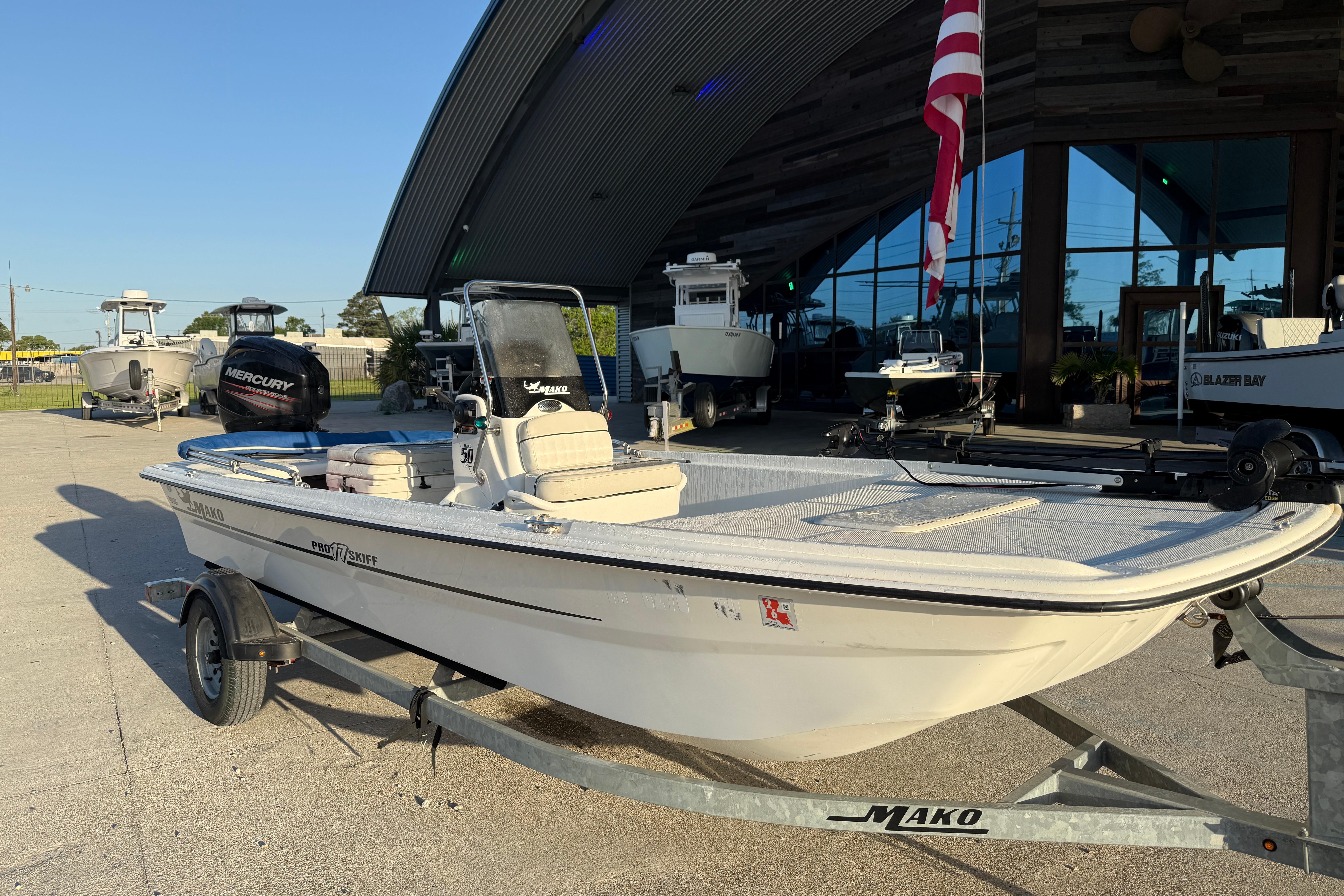 2017 Mako Pro Skiff 17 CC boat on trailer, parked outside a showroom.