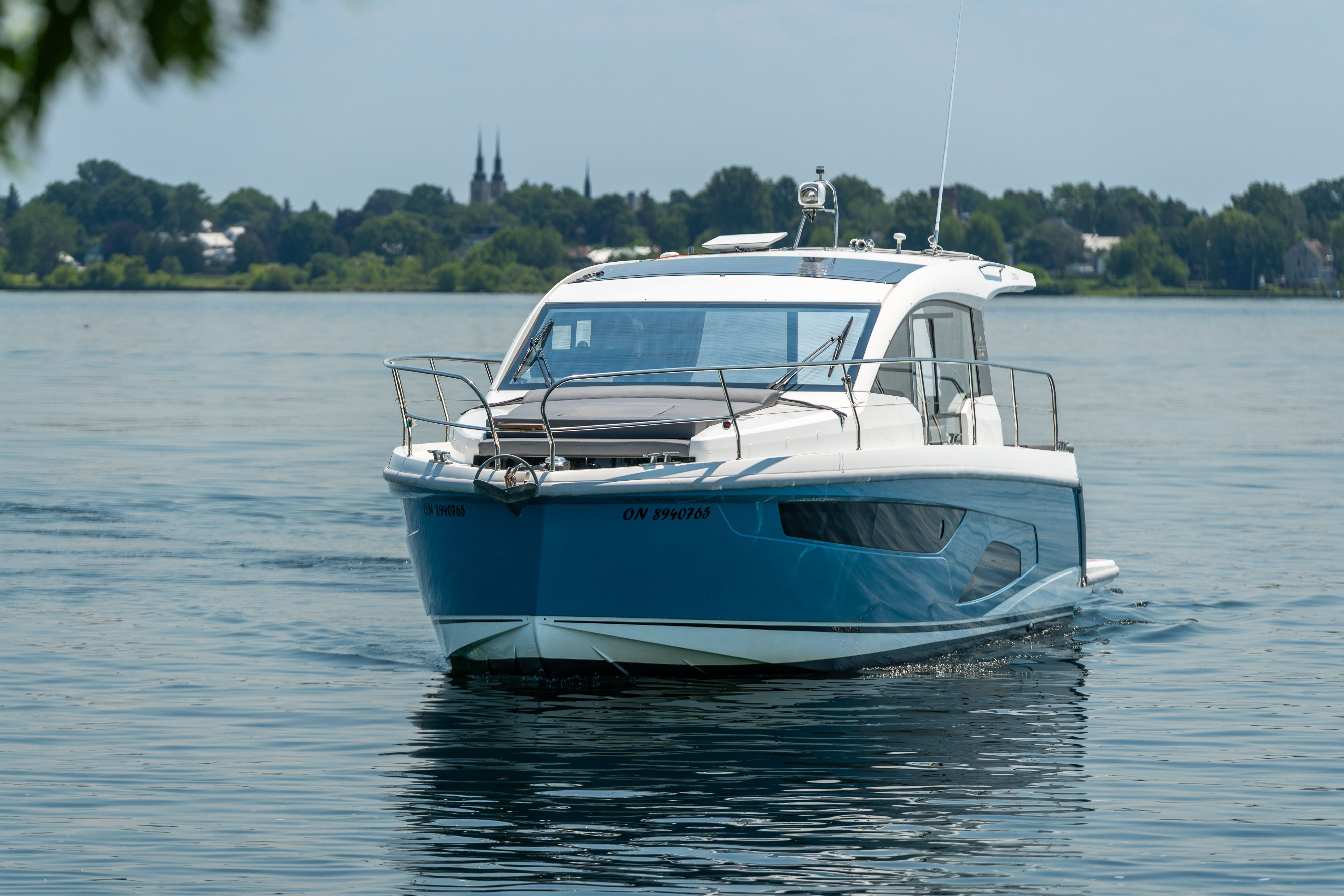 2023 Sealine C335V on calm water with a cityscape in the background.