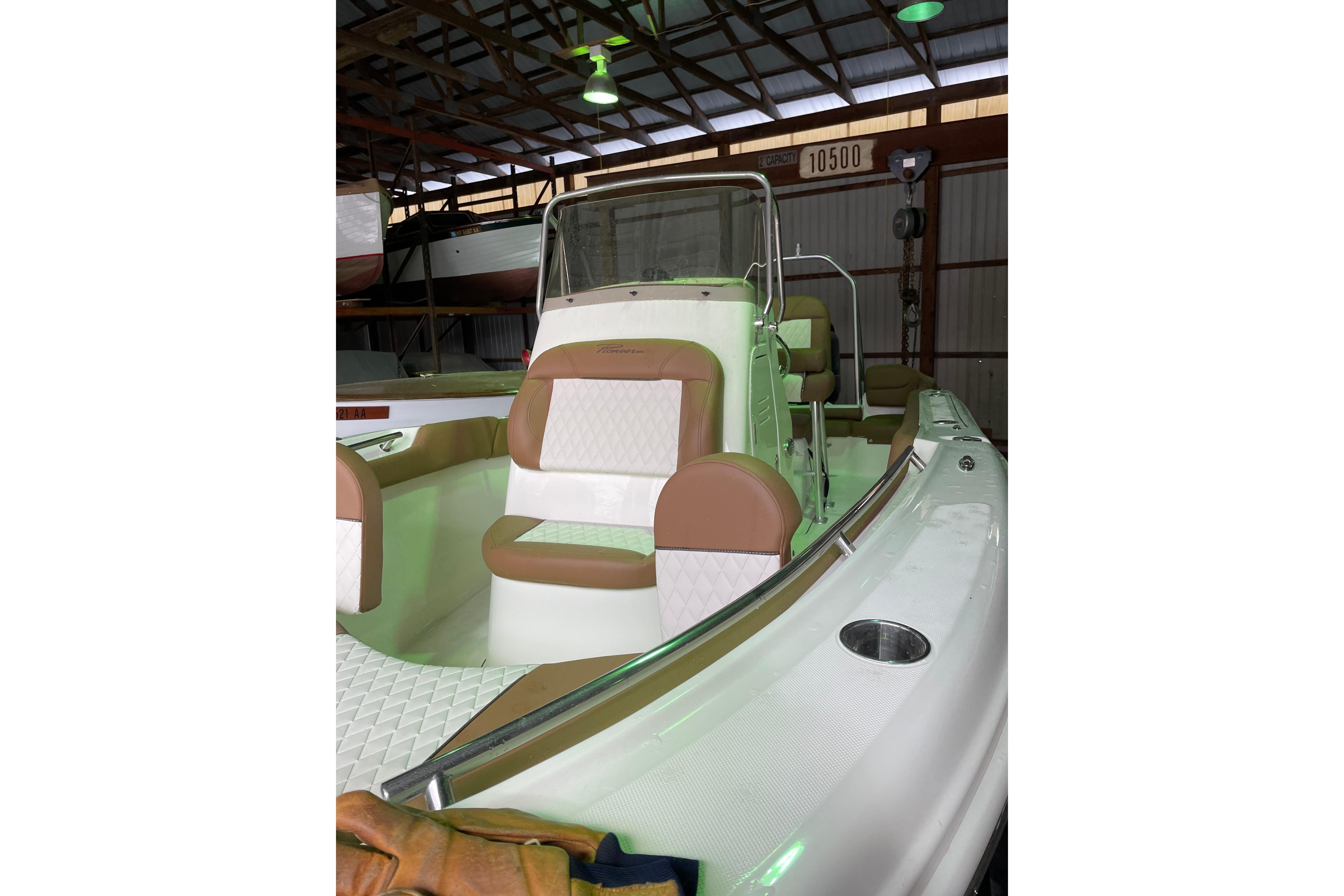 2026 Pioneer 202 Islander boat with tan and white seating in a storage facility.