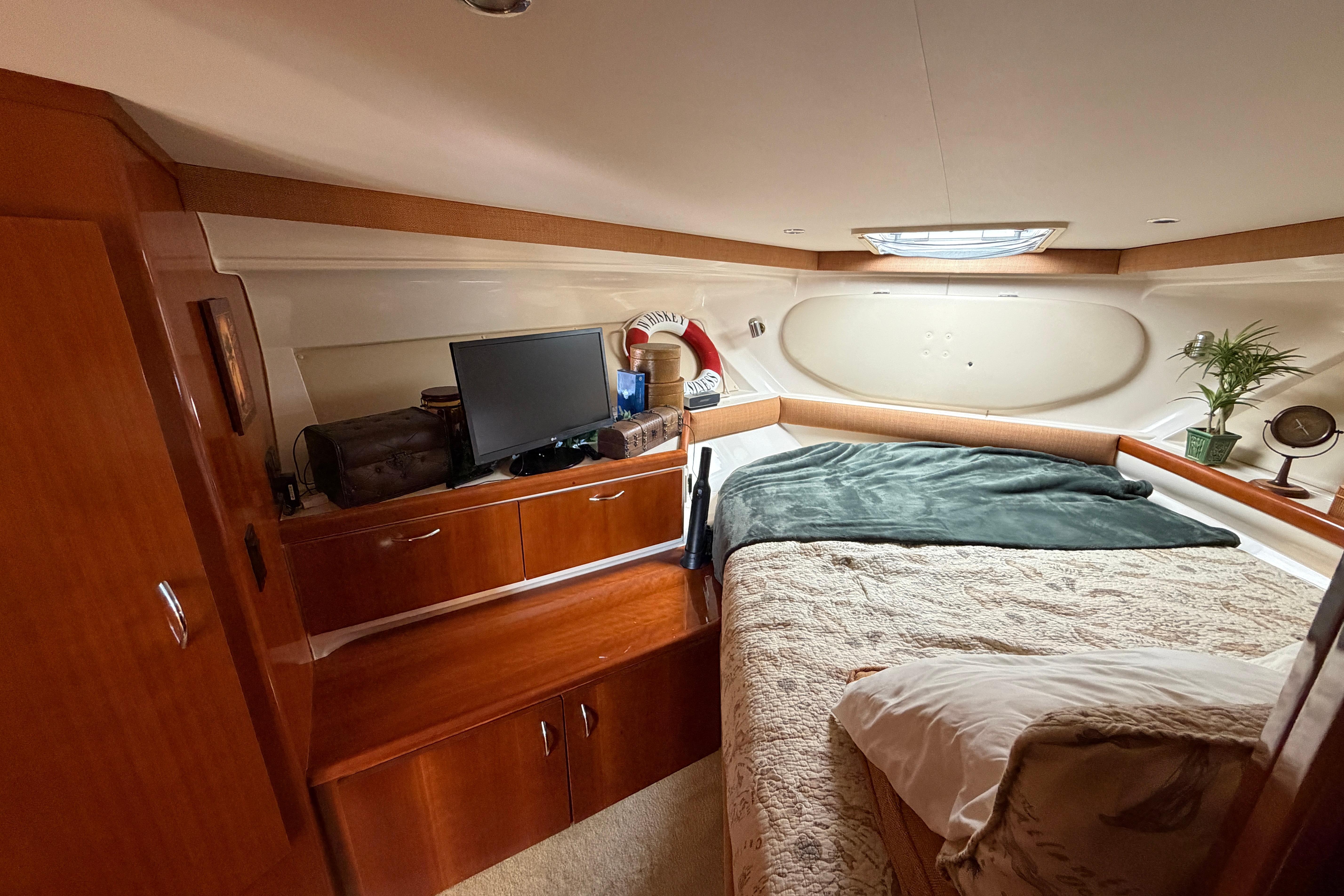 Cozy interior of 2003 Carver 350 Mariner yacht with bed, TV, and wooden cabinetry.