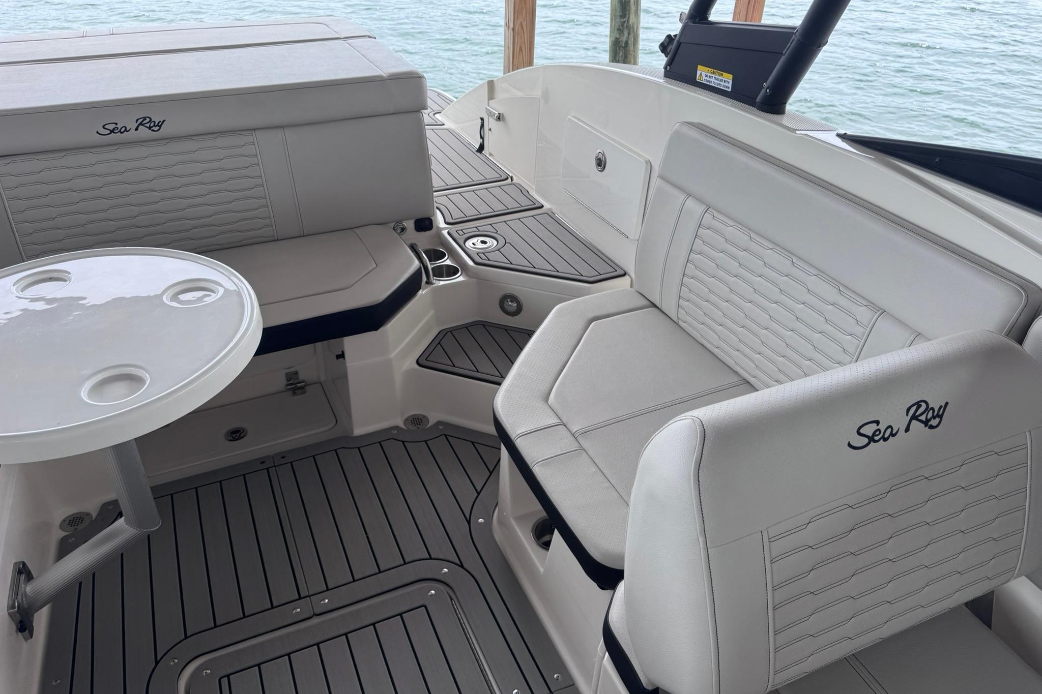 2021 Sea Ray SPX 230 boat interior with white seating and round table on water.
