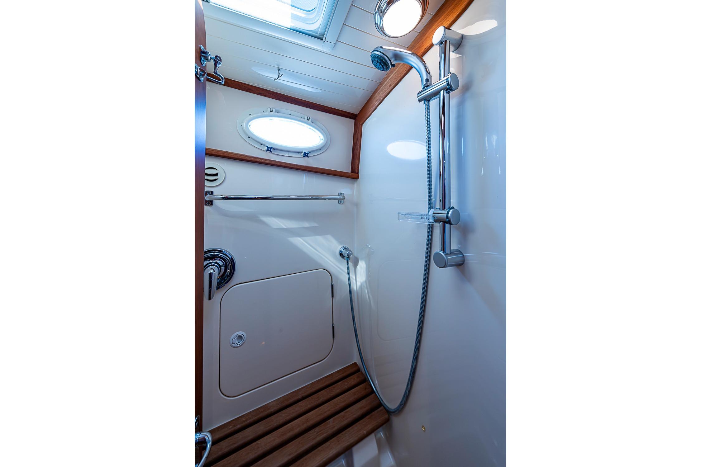 Shower area in 2008 Hinckley Talaria 44 MY yacht with wooden accents and porthole.