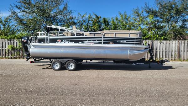 2023 Sun Tracker SportFish 22 XP3 pontoon boat on trailer, parked outdoors.