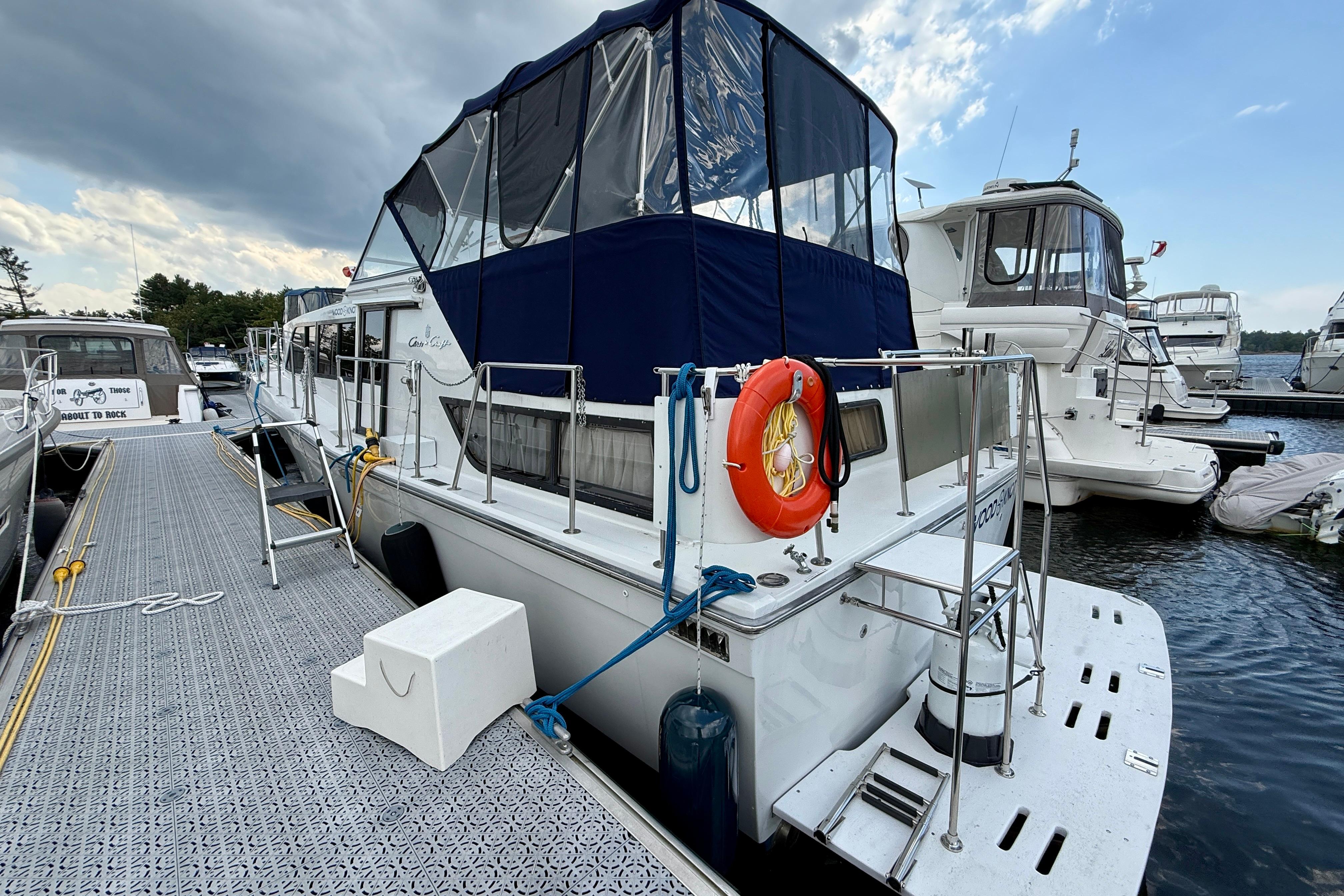 1988 Chris-Craft 381 Catalina yacht docked at marina, featuring blue canopy and lifebuoy.