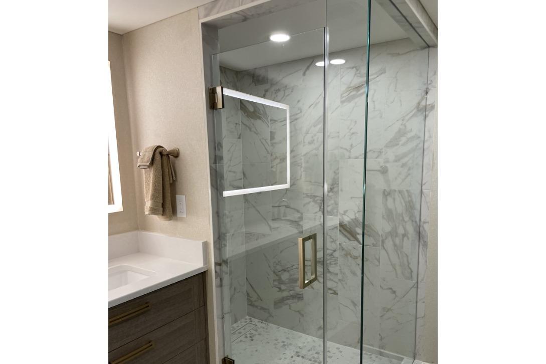 Modern bathroom with glass shower, marble tiles, and sleek fixtures in Adonia Max'd Out Trip model.