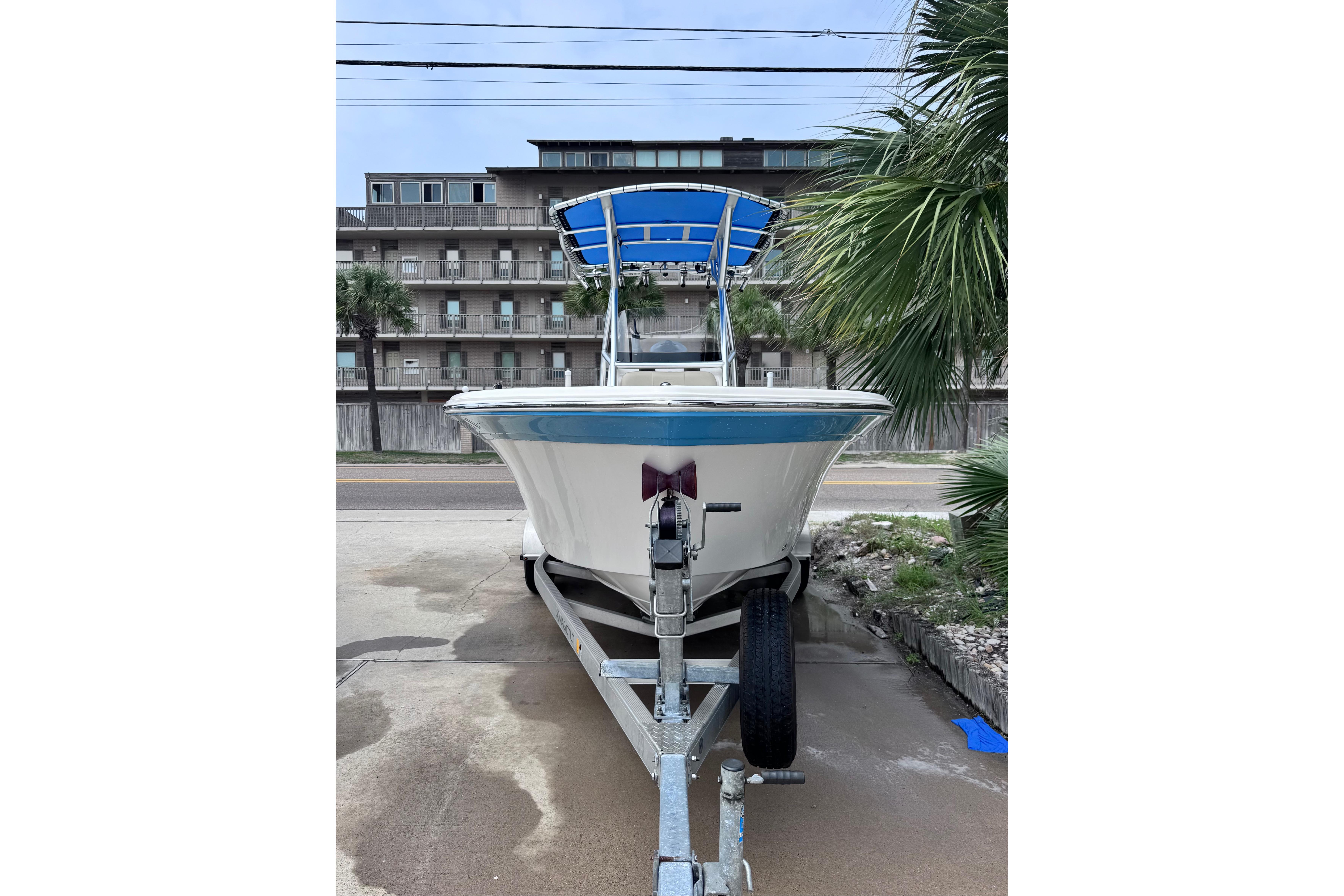 2018 Sea Fox 206 Commander boat on trailer, parked near palm trees and buildings.