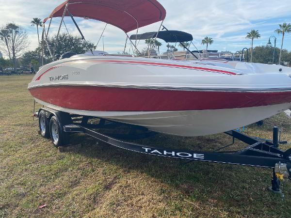 2022 Tahoe 2150 boat with red and white design on a trailer, parked on grass.