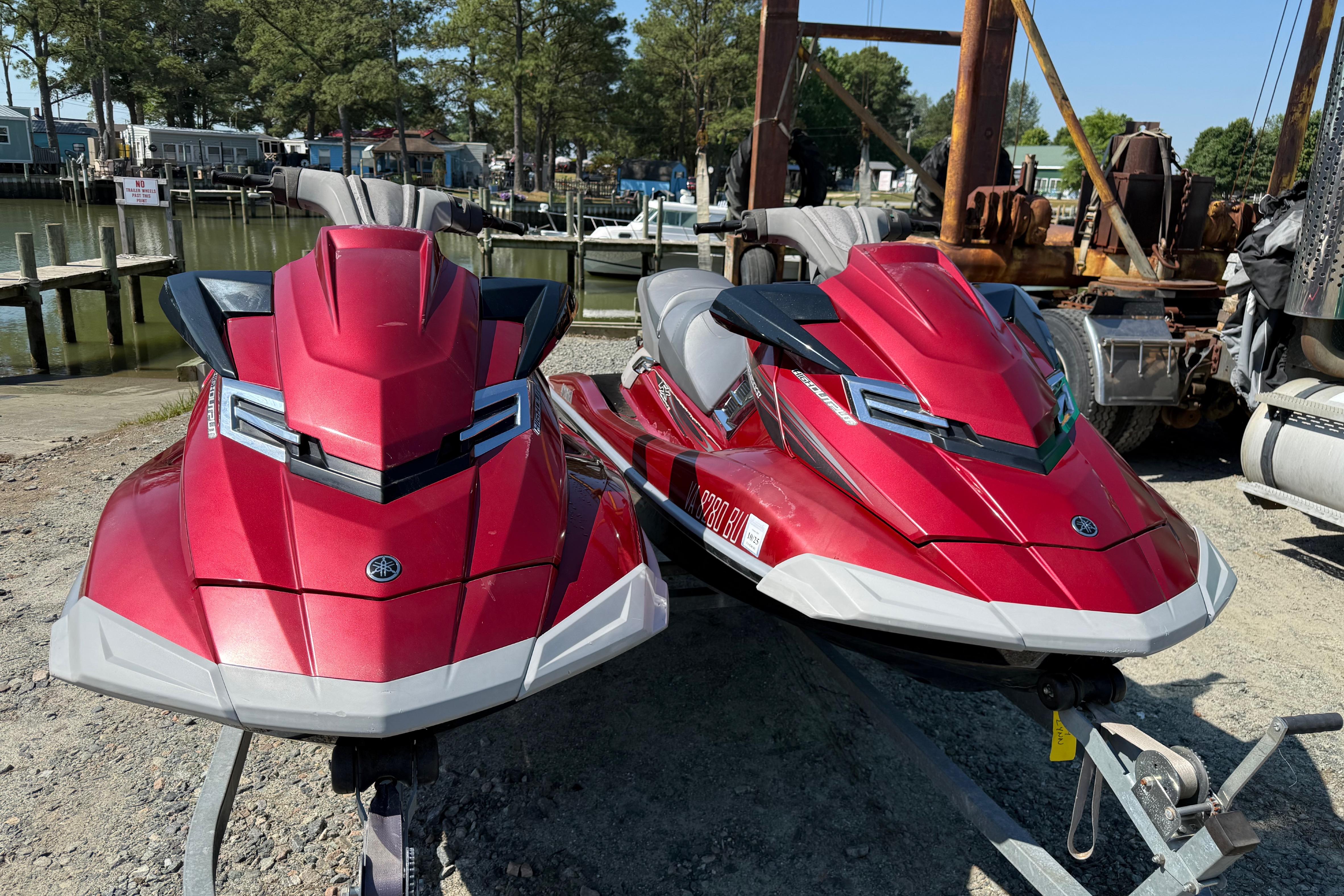 Two red 2013 Yamaha WaveRunner FX HO jet skis on a trailer by the water.