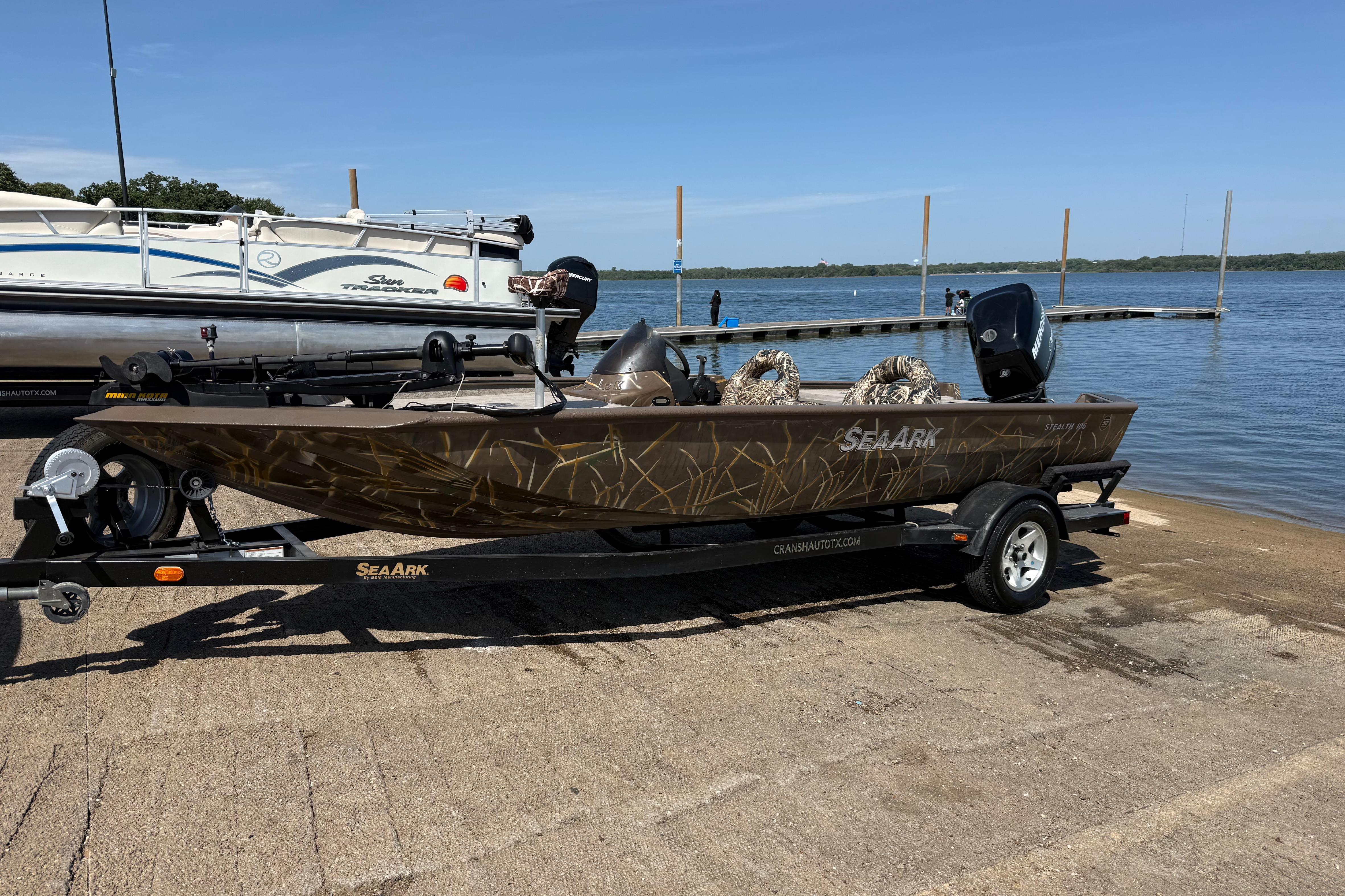 2010 SeaArk Stealth 190 boat on trailer by lake, featuring camouflage design.