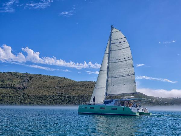 Sailing catamaran Vision 444 ES 2026 on serene lake with clear blue sky.