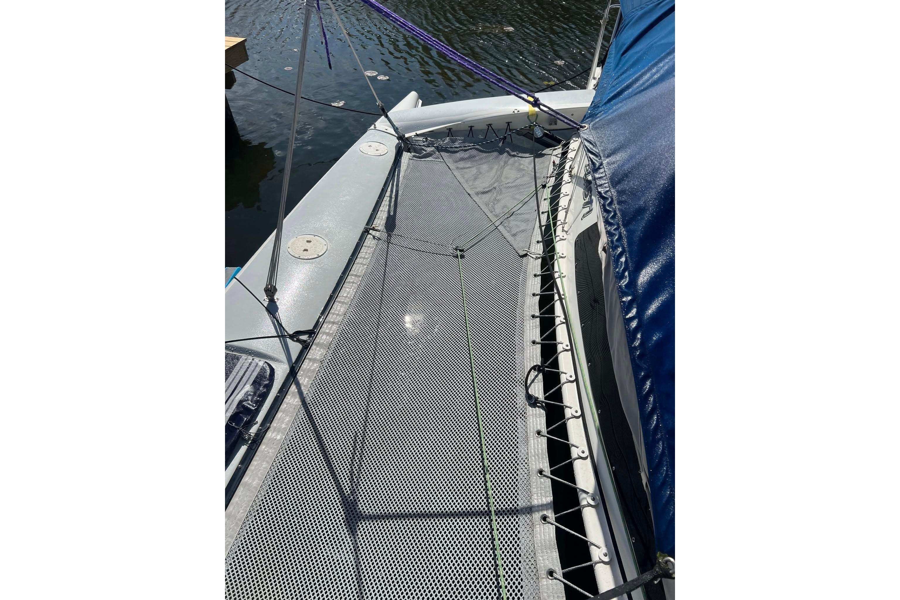 1993 Corsair F-27 sailboat deck with netting and blue cover on water.