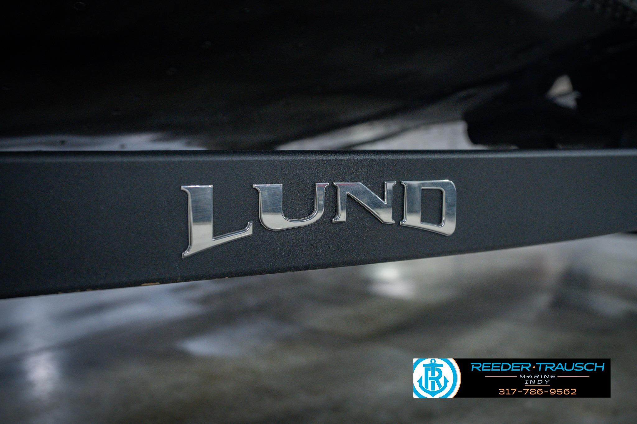 Close-up of 2026 Lund 1775 Impact XS boat logo on a dark surface.