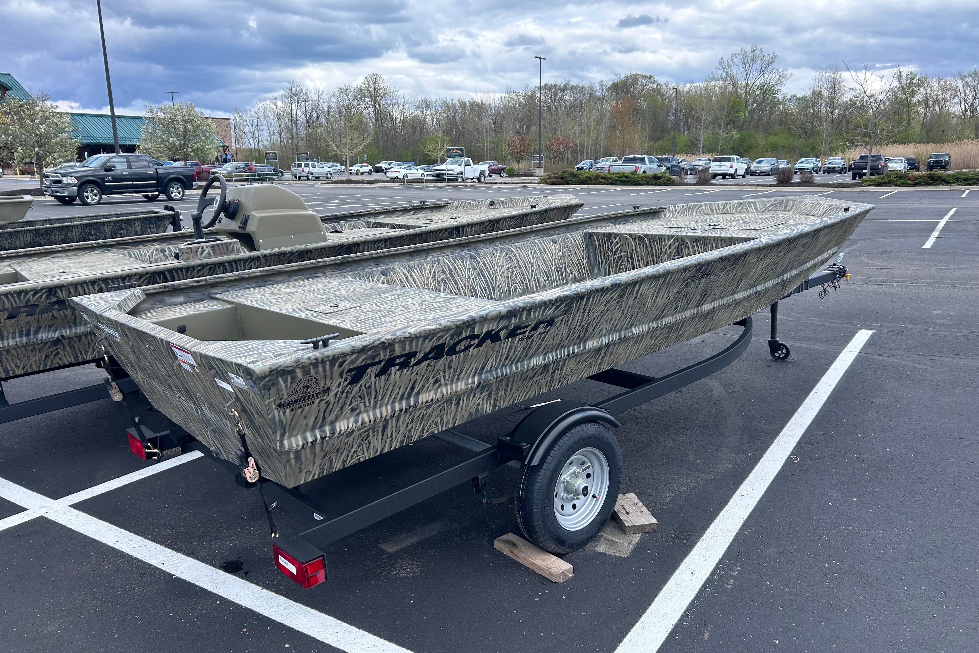 2026 Tracker Grizzly 1648 Utility boat in parking lot, featuring camouflage design.