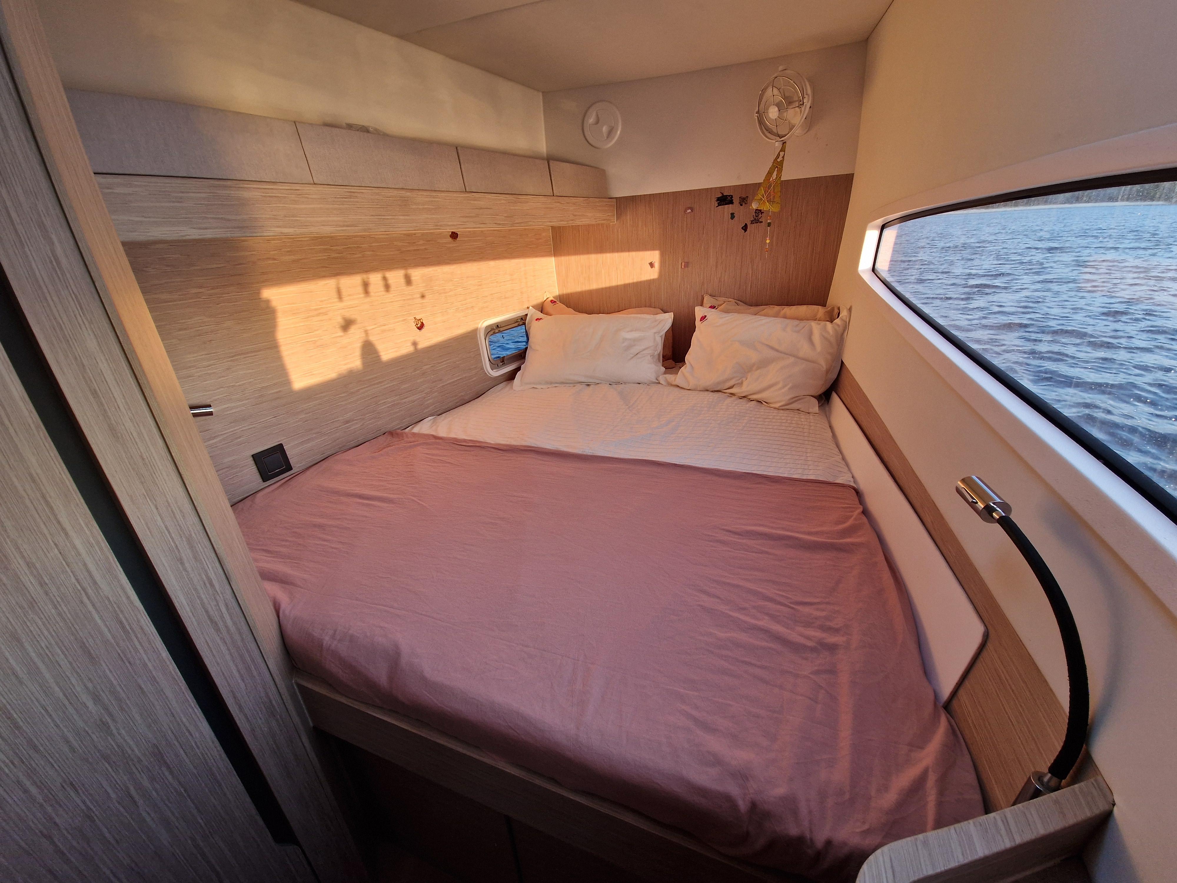 Cozy bedroom in 2023 Outremer 52 yacht with window view of the sea.