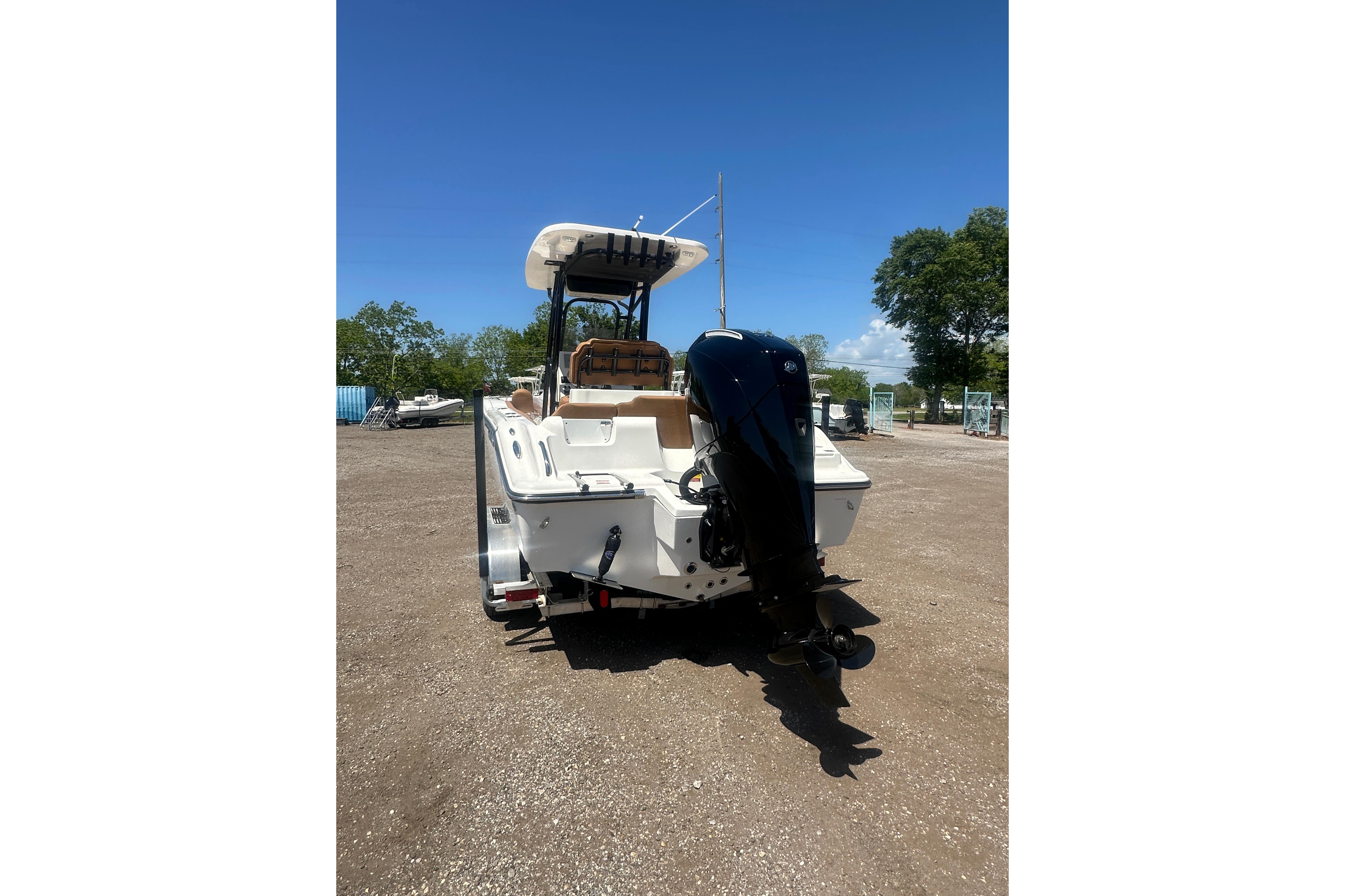 2026 Key West 239 FS boat with outboard motor, parked on gravel under clear blue sky.