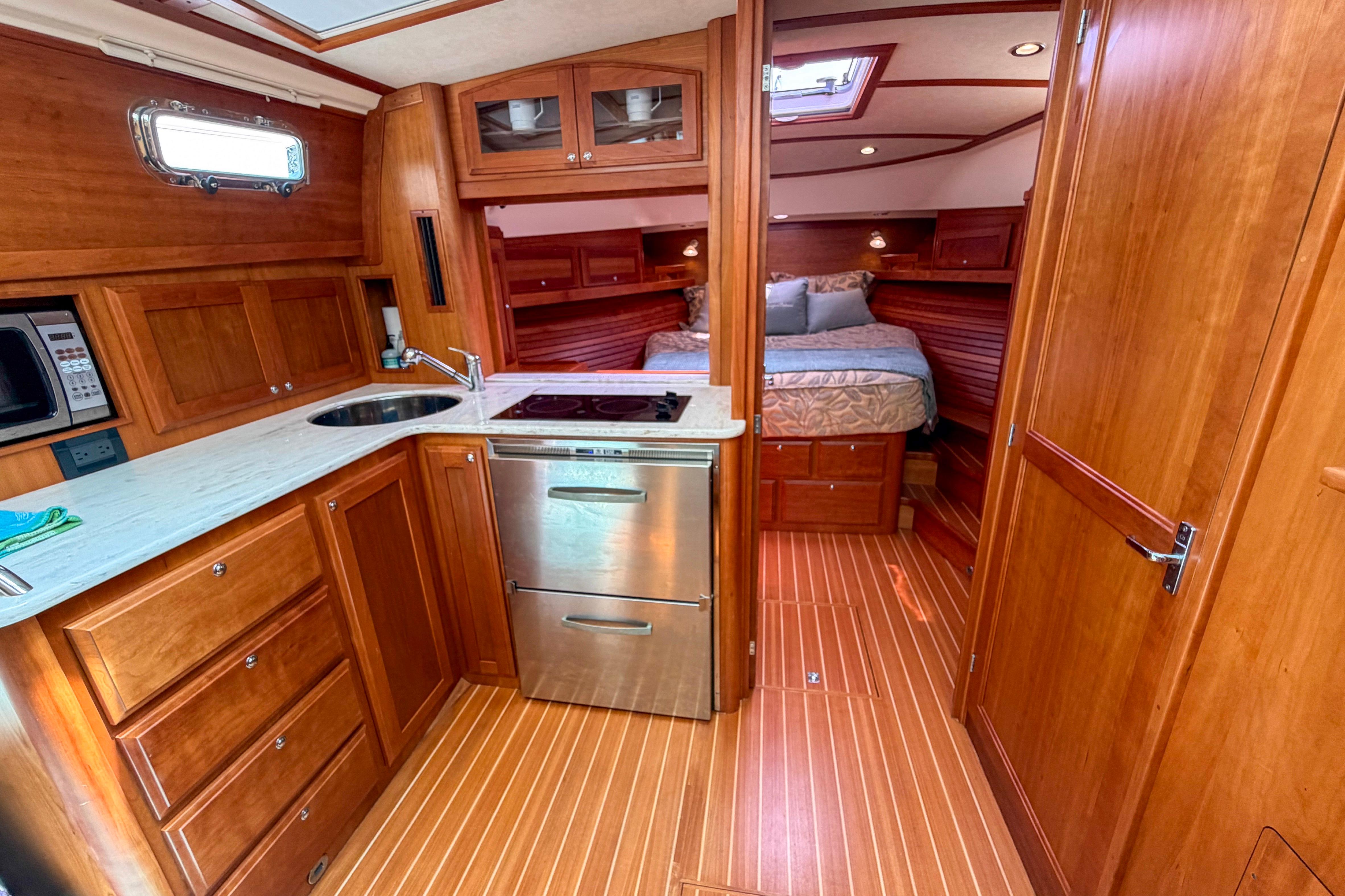 2013 Sabre 38 Salon Express interior with wood cabinetry, compact kitchen, and cozy bedroom.
