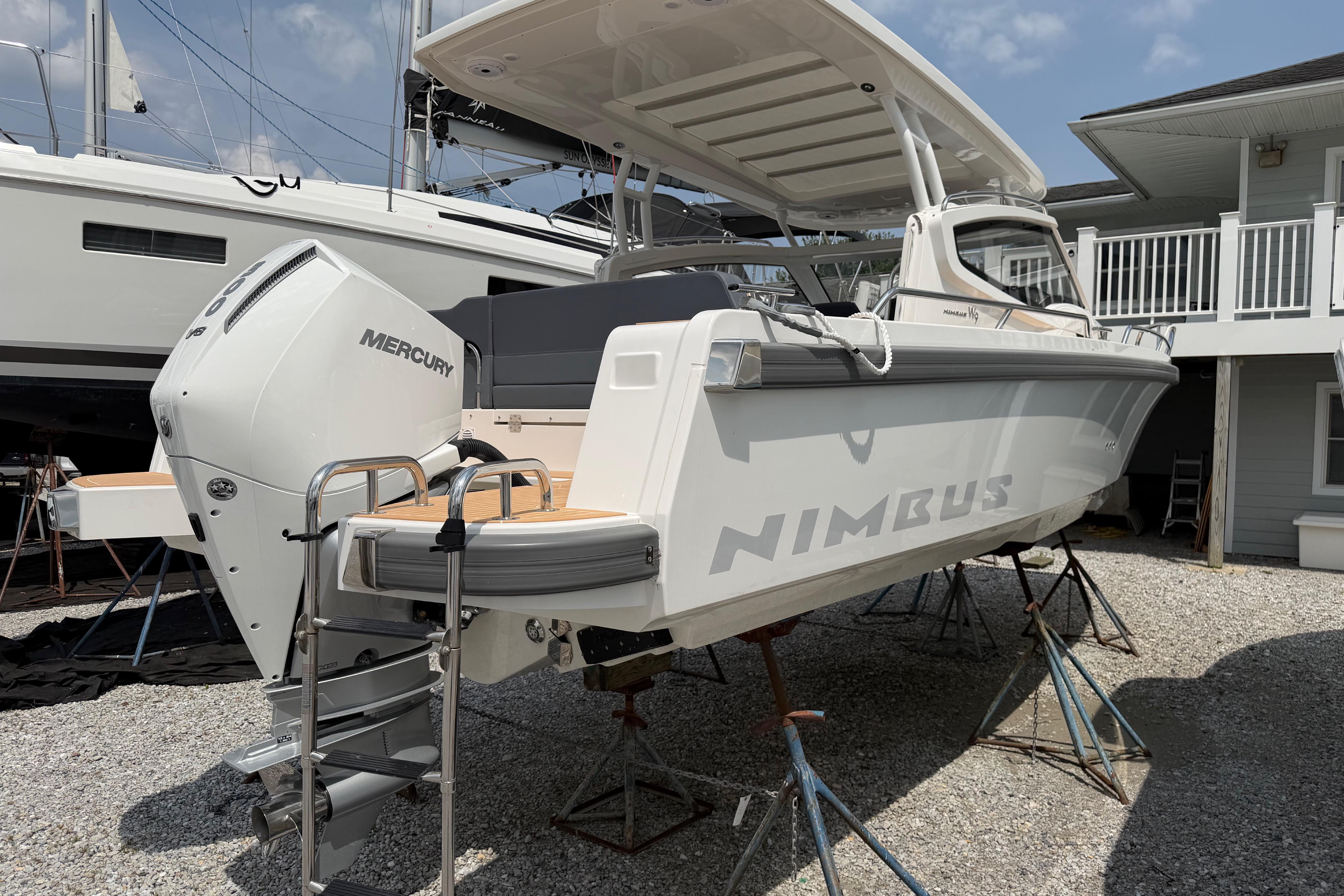 2025 Nimbus Weekender 9 boat with Mercury engine, elevated on stands in a marina.