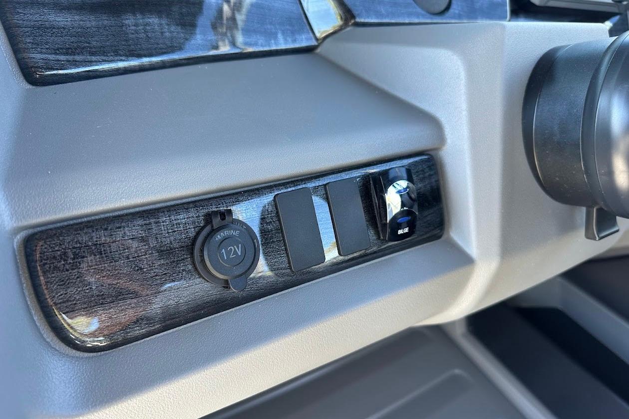 Dashboard controls of 2026 Tahoe Pontoon LTZ Quad Lounger Shift 23 with 12V marine outlet.
