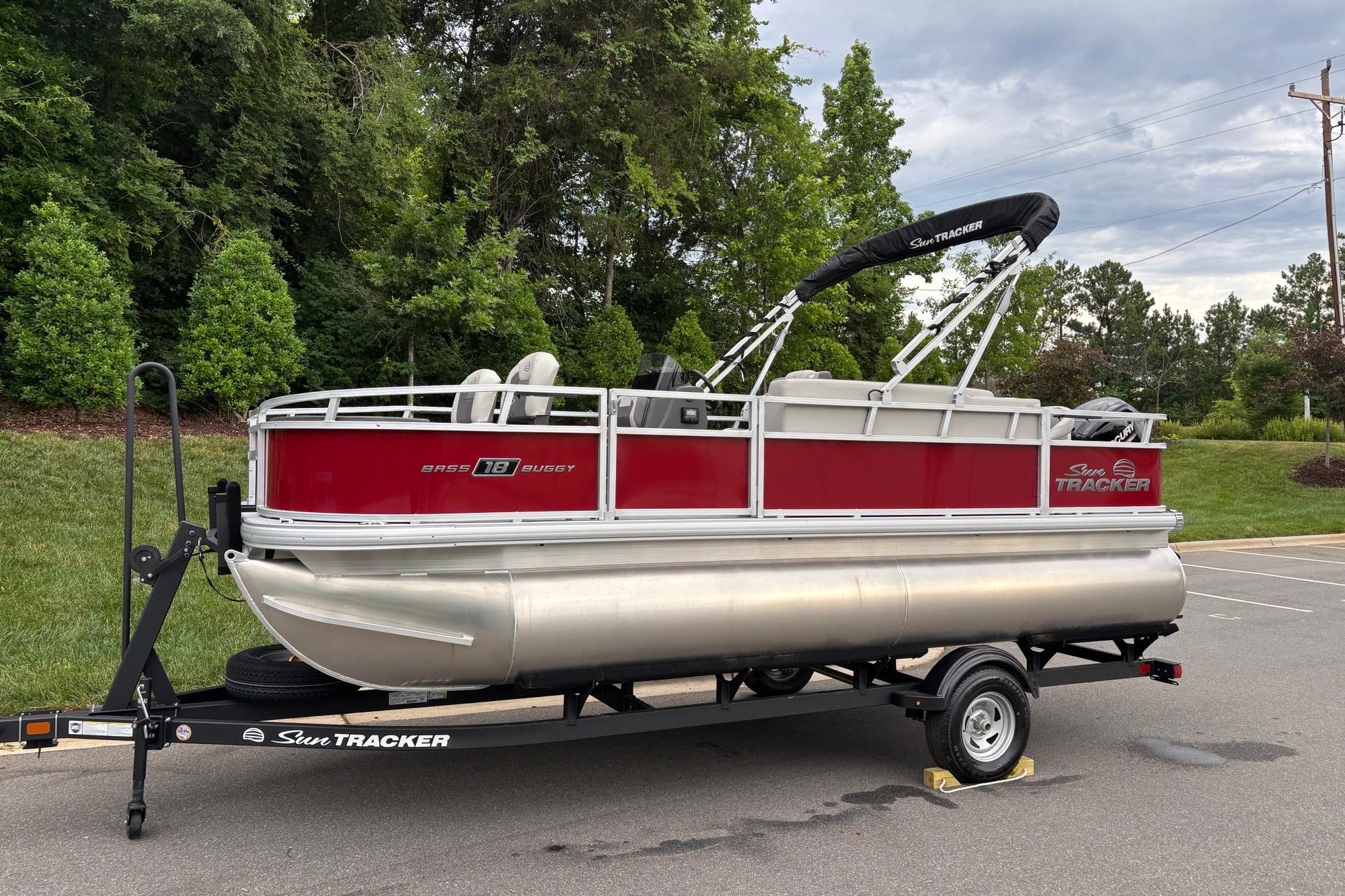 2026 Sun Tracker Bass Buggy 18 DLX pontoon boat on trailer, parked outdoors.