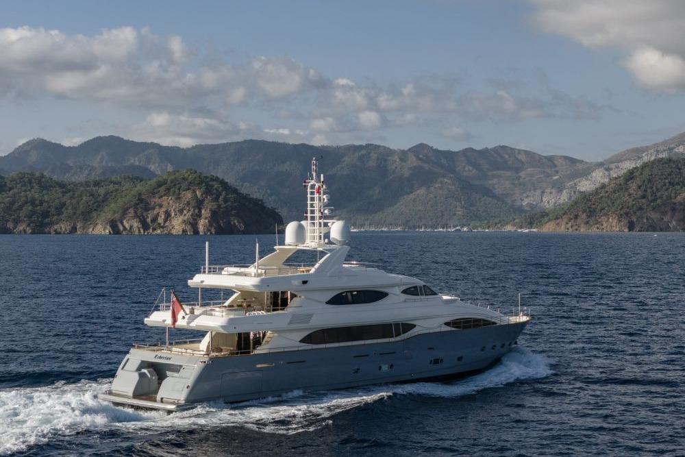 Luxurious 2009 CRN 129 yacht cruising near scenic mountainous coastline.