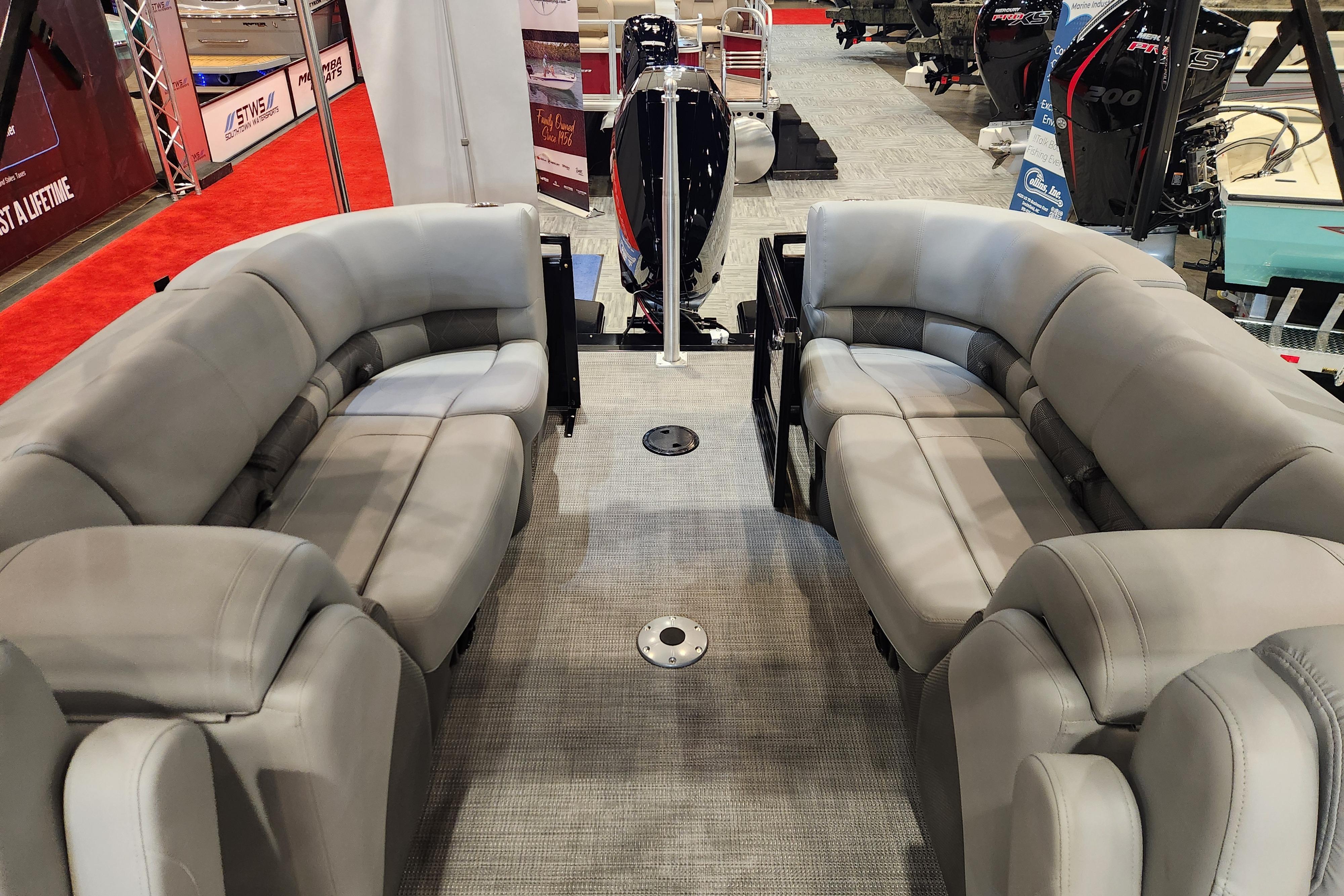 2025 Regency 250 LE3 pontoon boat interior with plush gray seating at a boat show.