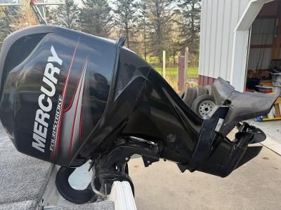 A Mercury outboard motor is attached to a boat on a trailer.