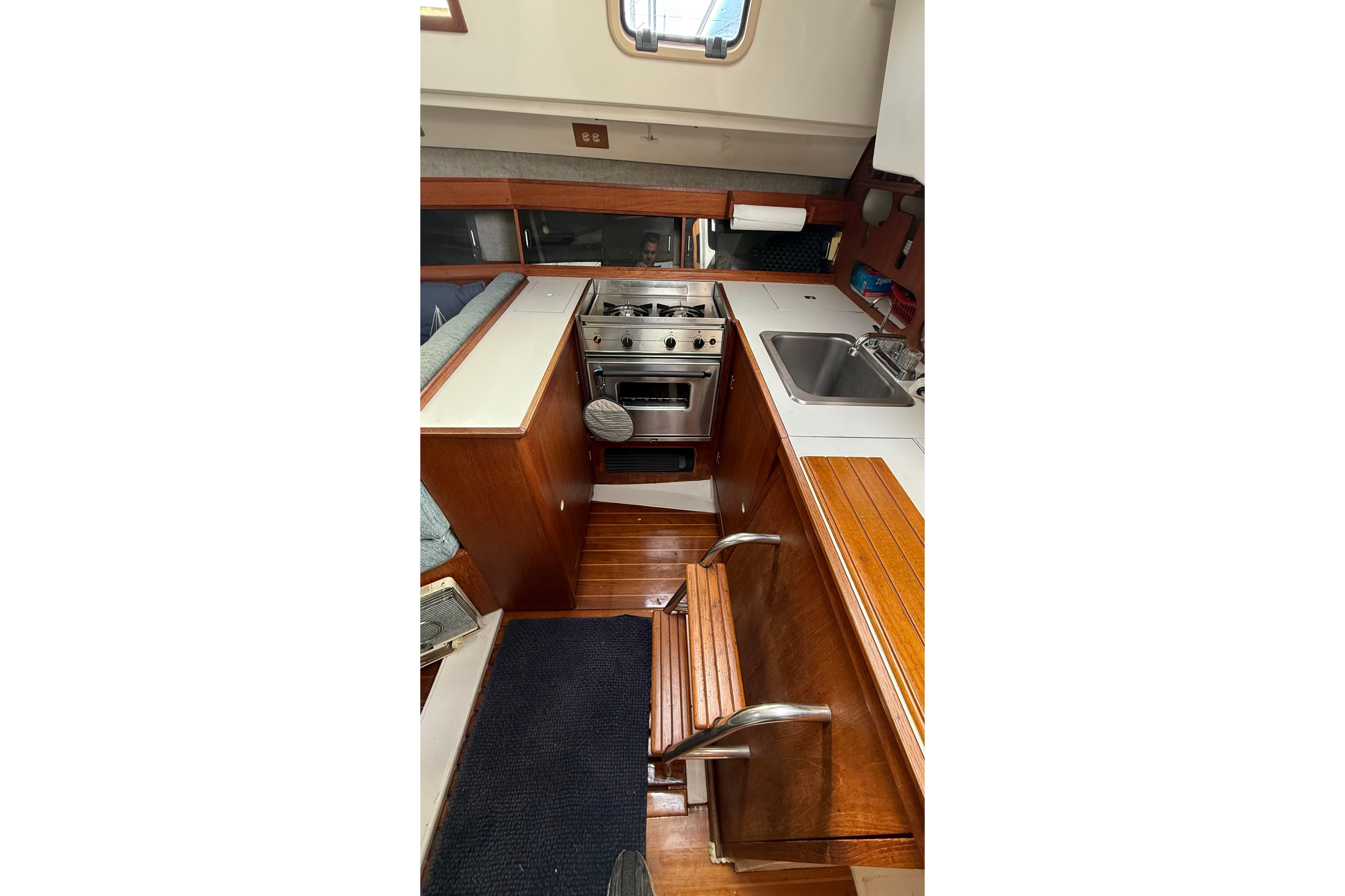 1984 Hunter 31 yacht interior kitchen with stove, sink, and wooden cabinetry.