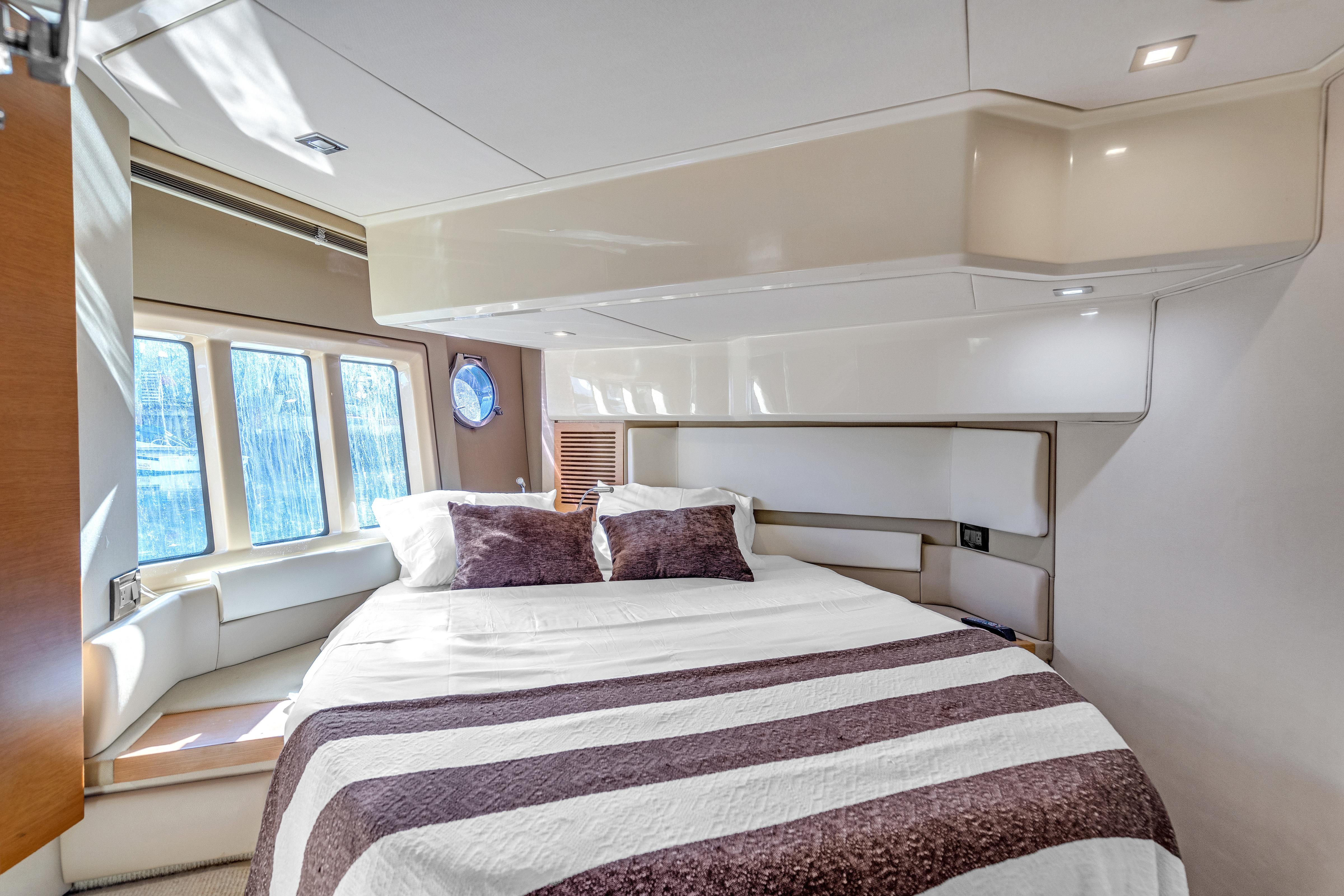 Luxurious bedroom interior of 2013 Azimut 45 Flybridge yacht with large windows and cozy bedding.