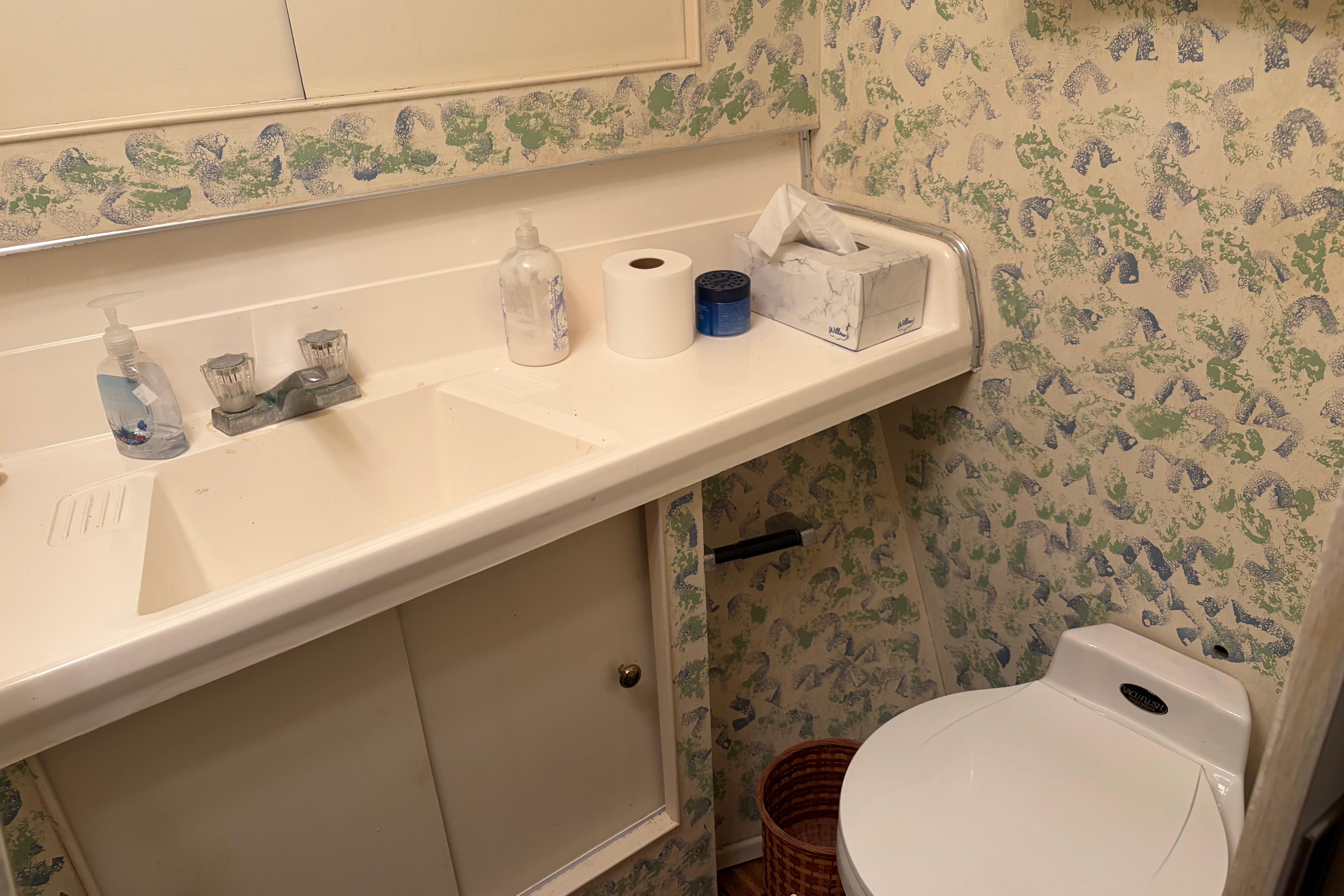 Bathroom interior of 1971 Chris-Craft 42 Commander with sink, toilet, and patterned wallpaper.