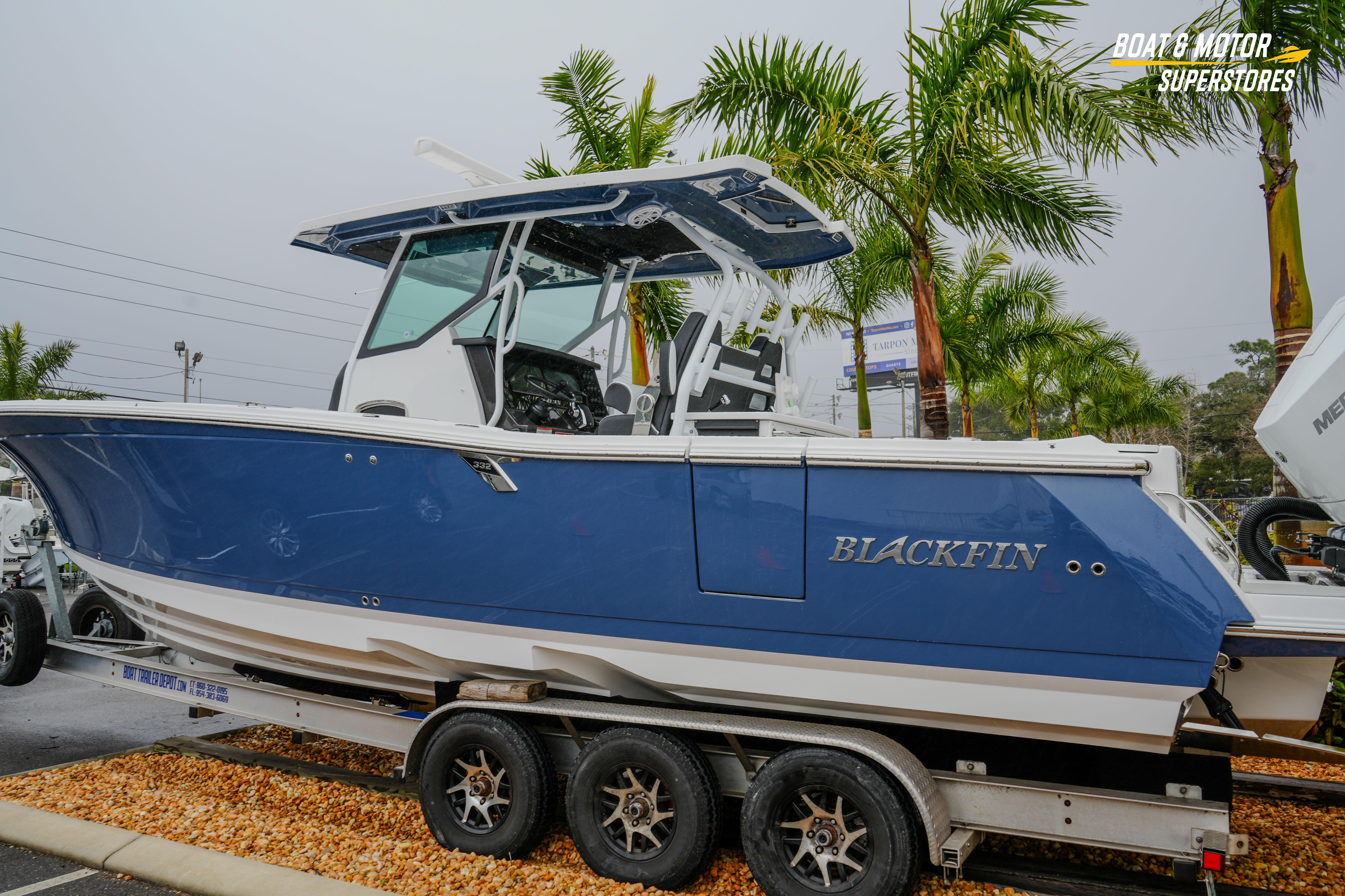 2026 Blackfin 332 CC boat on trailer, blue hull, palm trees in background.