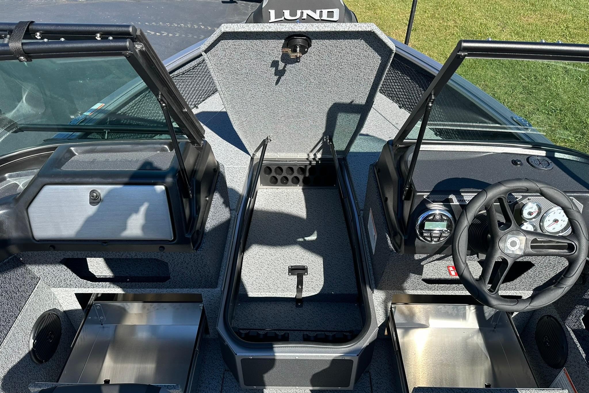2026 Lund 1875 Impact XS Sport boat interior with steering wheel and open compartments.