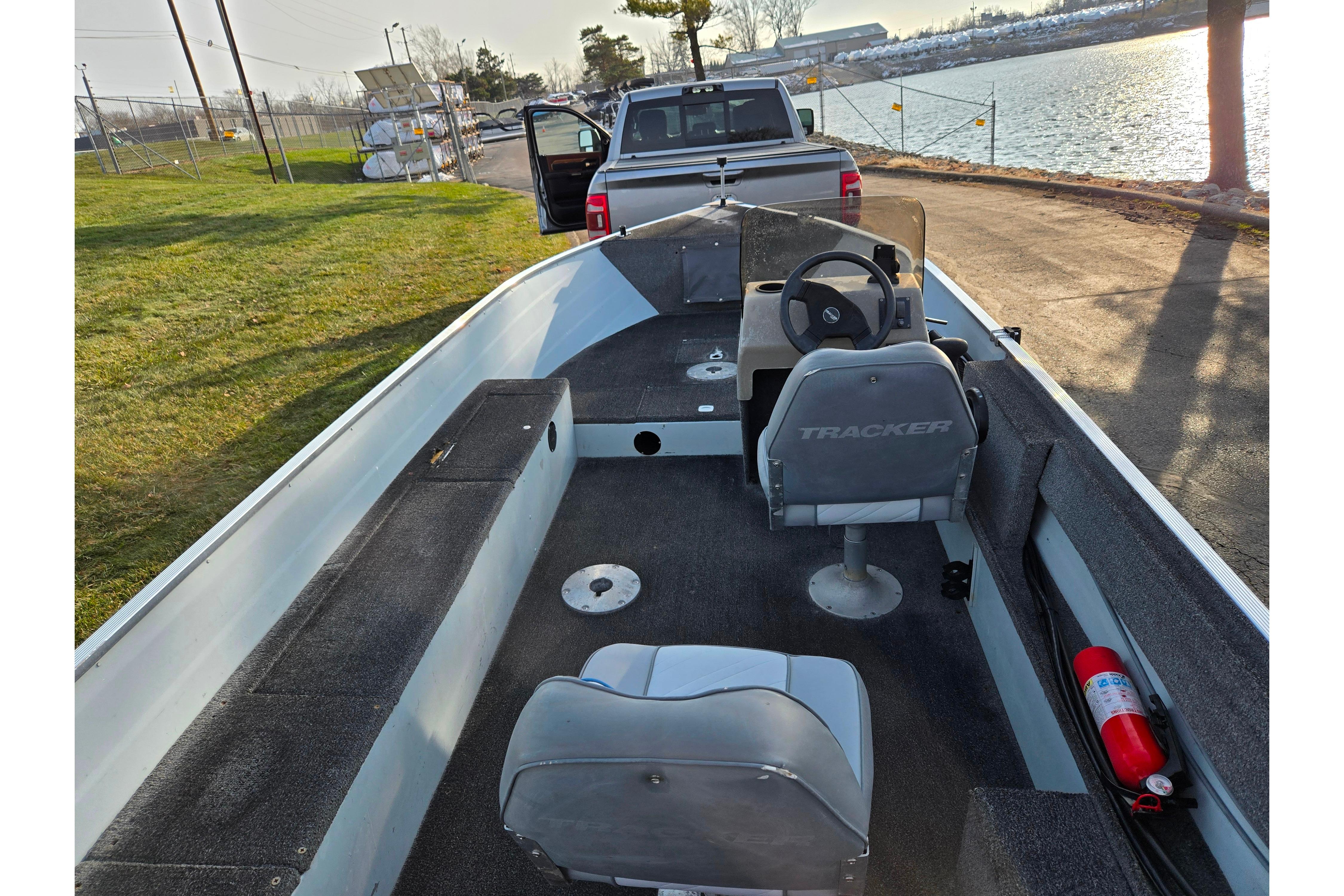 1994 Tracker Pro Deep V-16 boat interior with steering wheel, seats, and fire extinguisher by a lake.