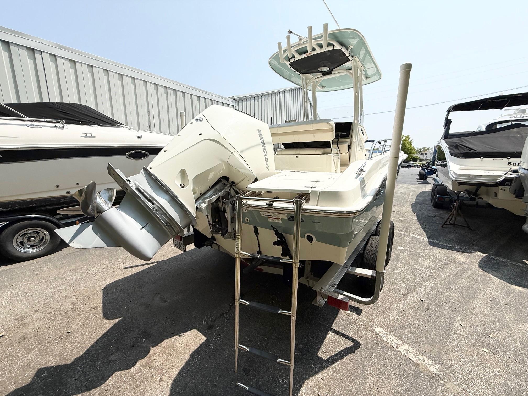 2022 Boston Whaler 220 Dauntless boat with outboard motor and ladder, parked outdoors.