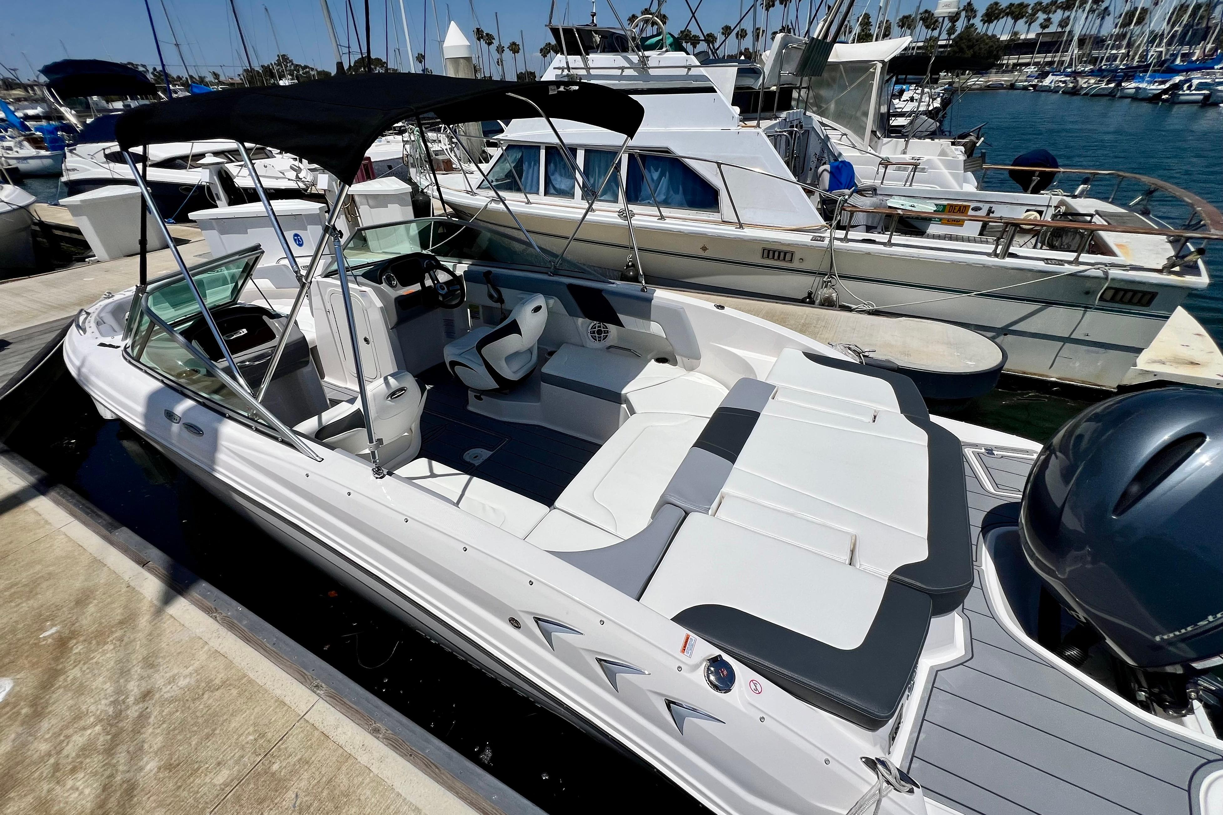 2022 Chaparral 230 SSi boat docked at marina, featuring sleek design and spacious seating.