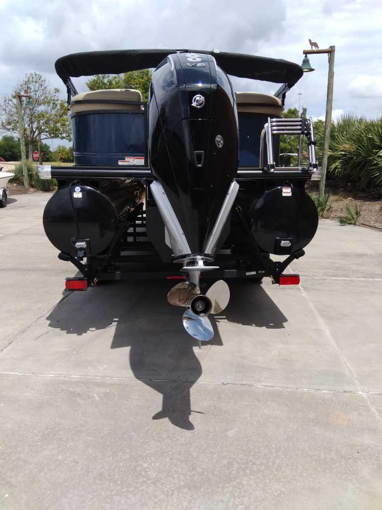 2025 Regency 250 LE3 pontoon boat with powerful outboard motor, parked on concrete.