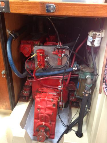 A red engine in a boat's engine compartment with hoses and wires.