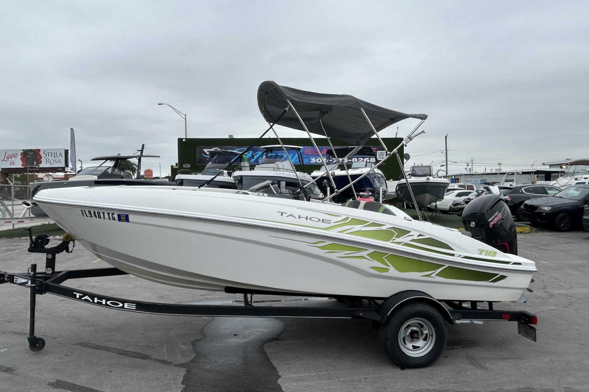 2022 Tahoe T18 boat on trailer, white with green accents, parked outdoors.