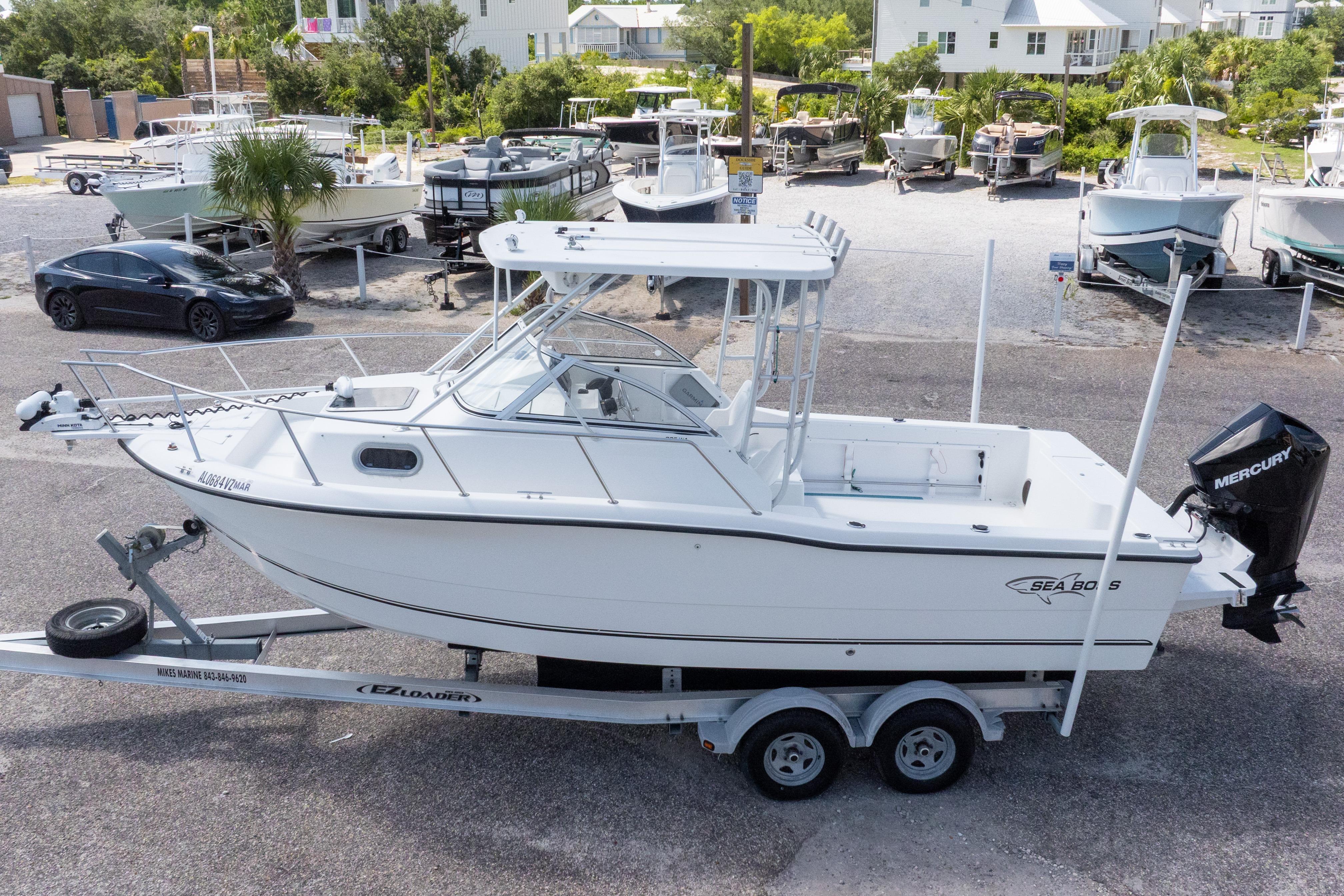 2007 Sea Boss 235 Walkaround boat on trailer, parked in a marina with other boats.