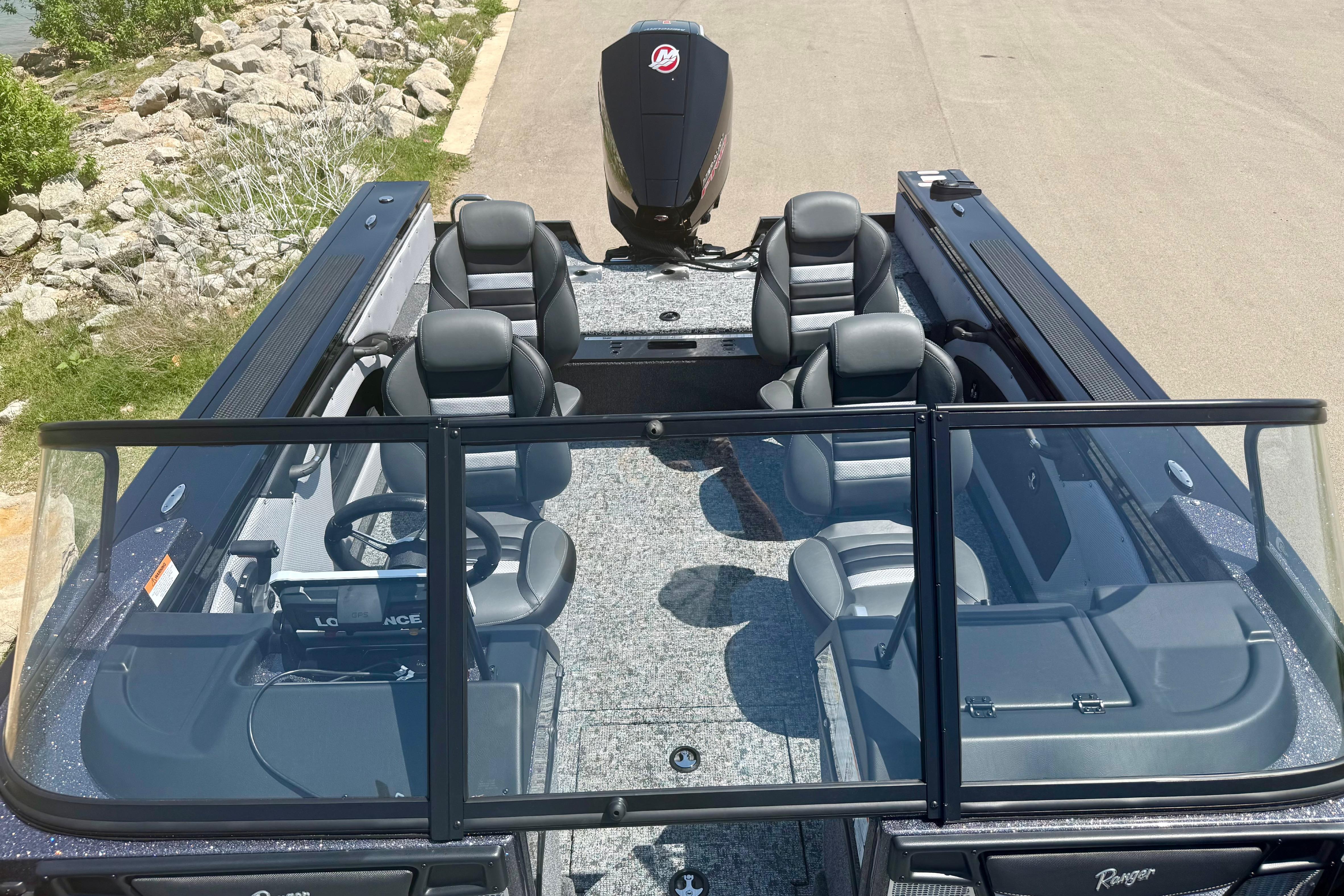 2026 Ranger VX1788 WT boat interior with seating and steering console, docked near rocky shoreline.