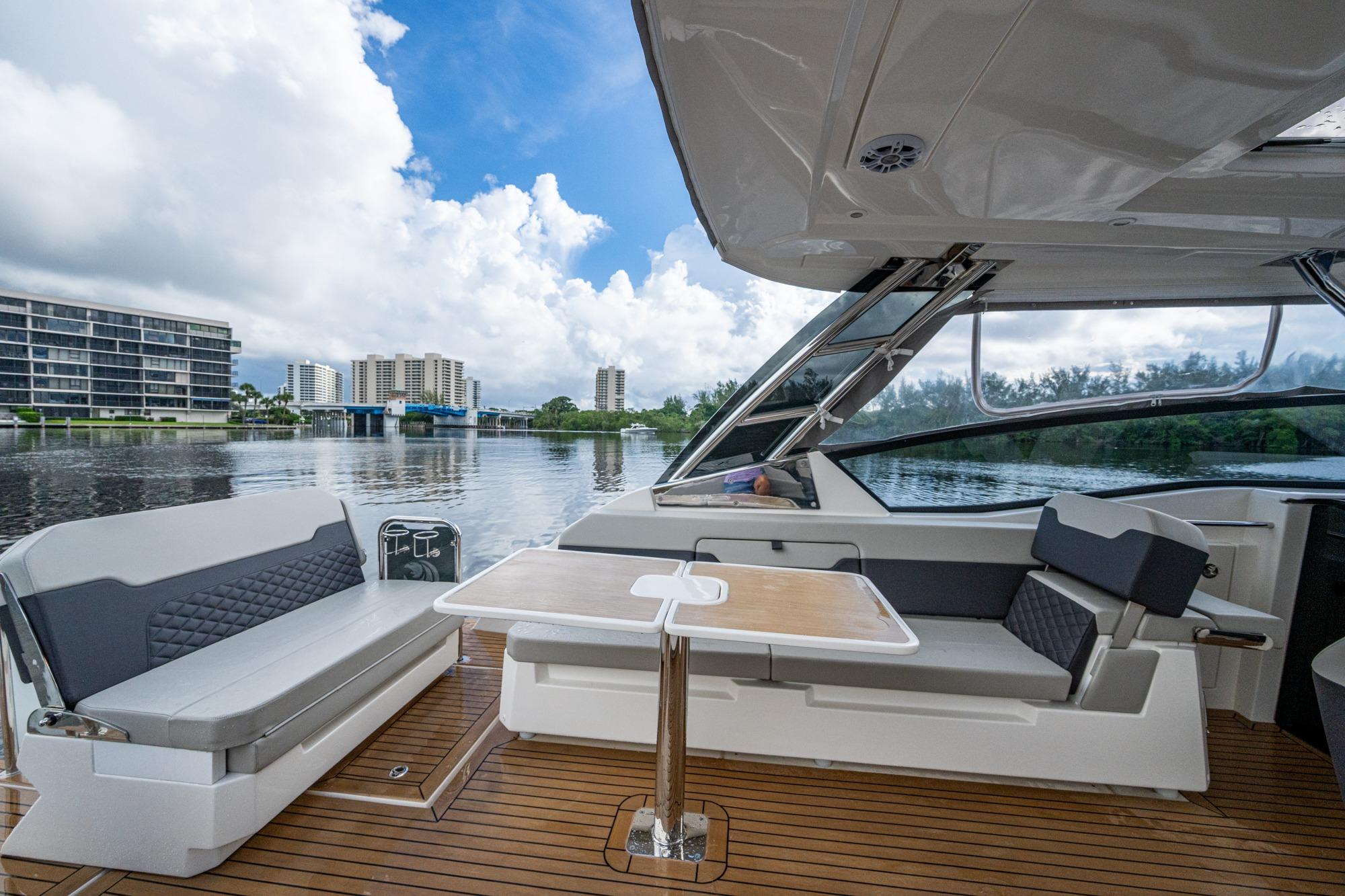 2023 Aquila 32 Power Cat interior with seating and table, overlooking waterfront cityscape.