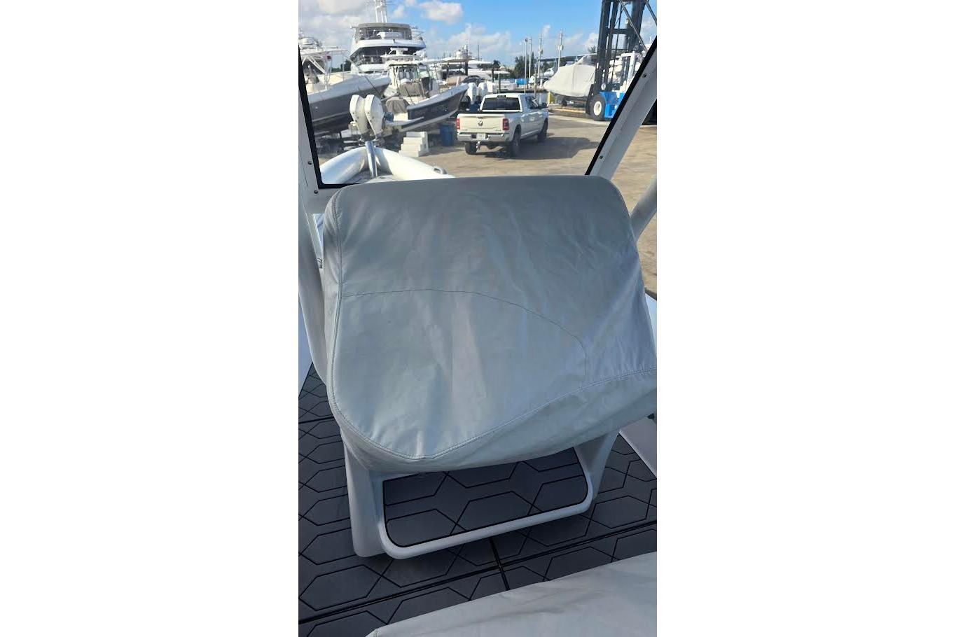 Covered seat on 2024 Airship 310 boat, docked with other vessels in background.