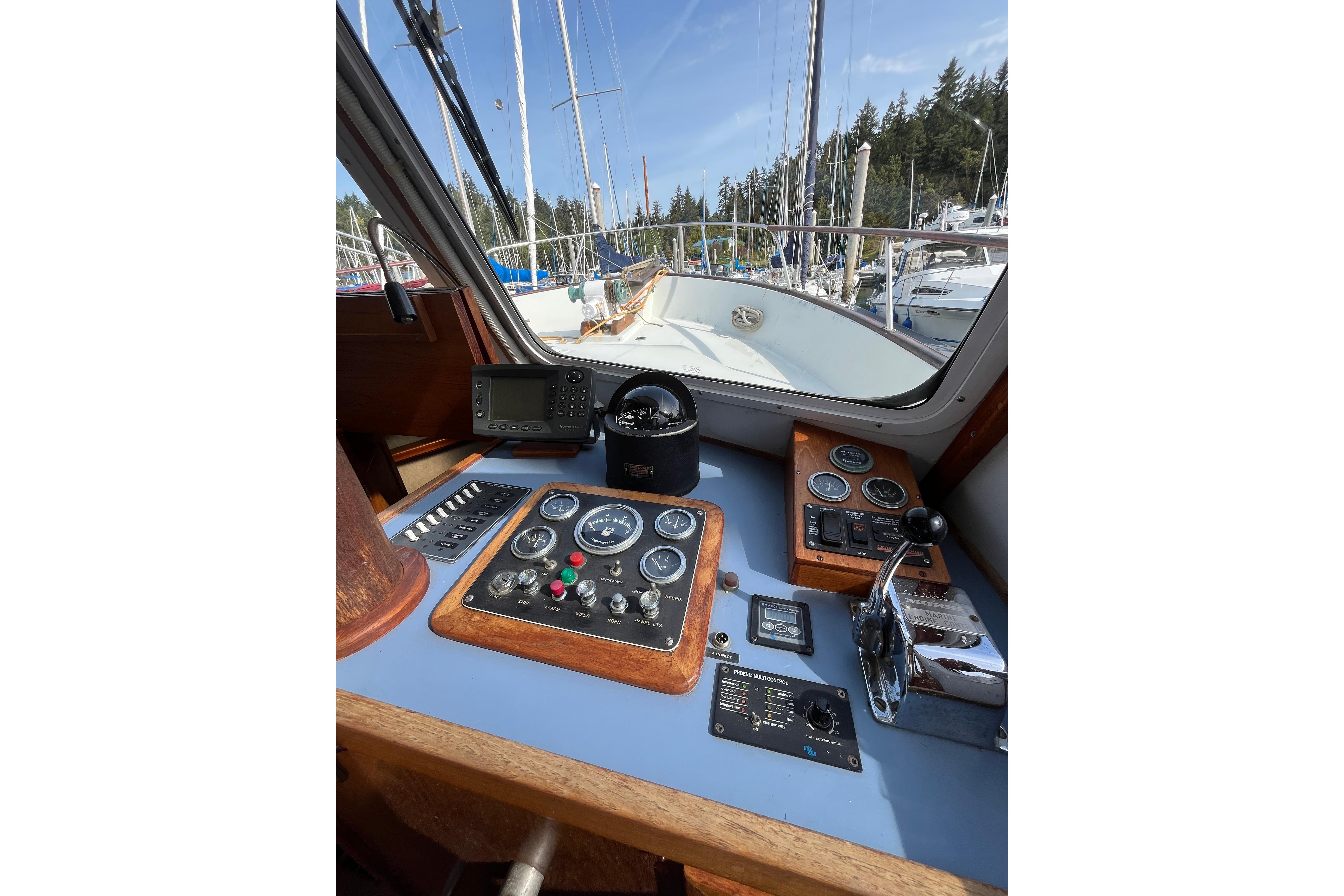 1974 DeFever 40 yacht helm with navigation instruments and controls, docked in a marina.
