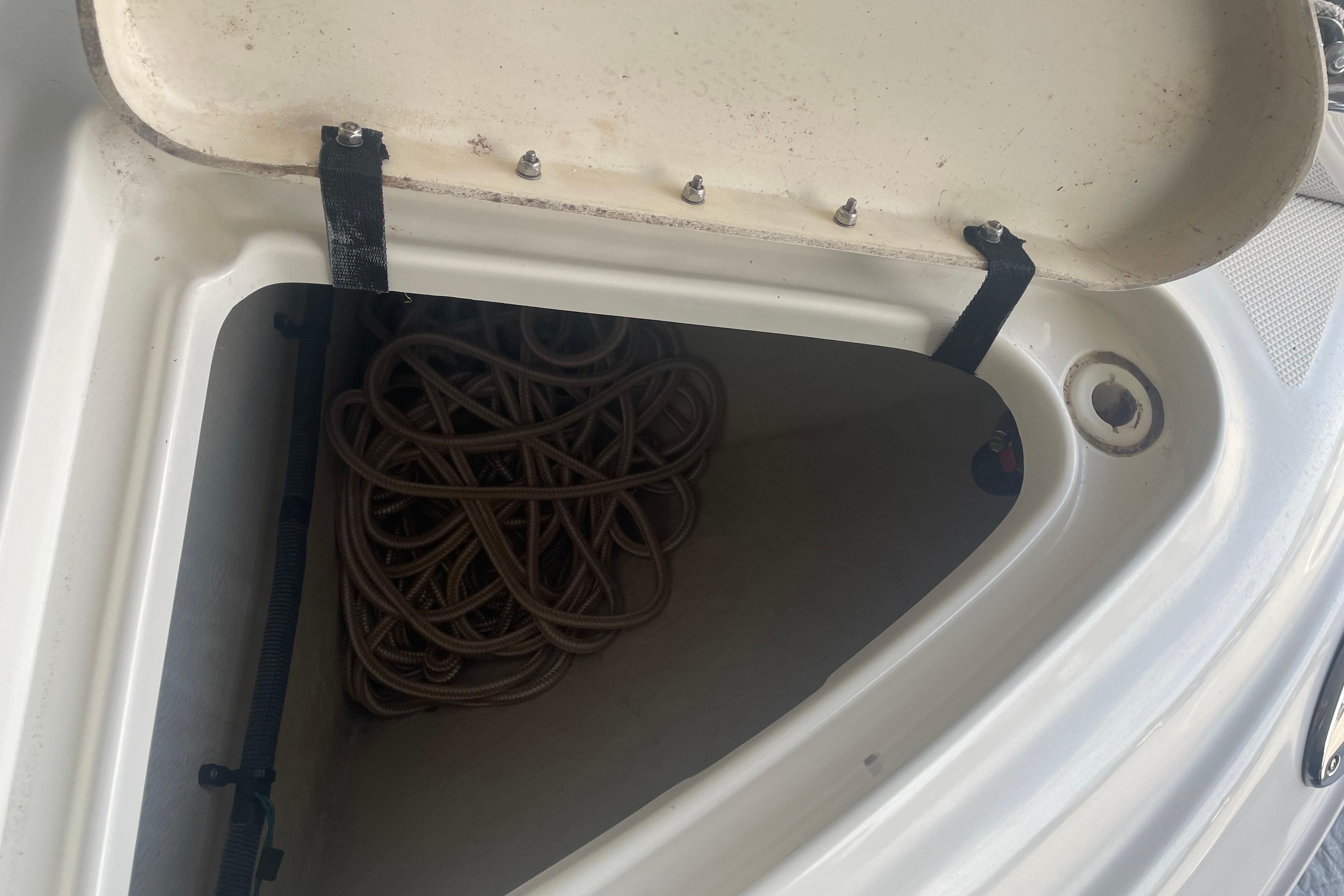 Open storage compartment on 2006 Sea Ray Sundancer 260 boat with coiled rope inside.