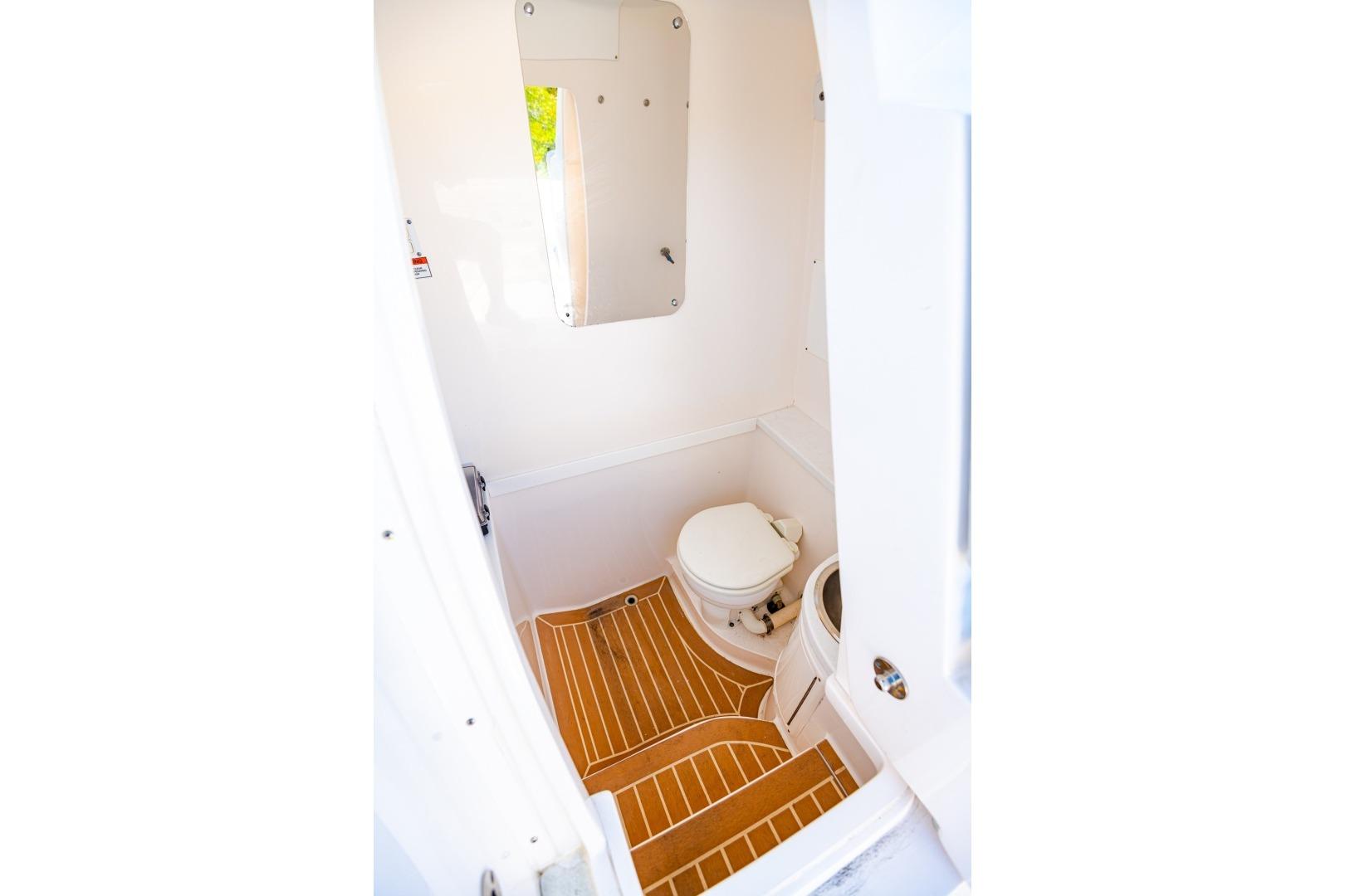 Interior of 2018 Intrepid 327 Center Console boat bathroom with wooden flooring.